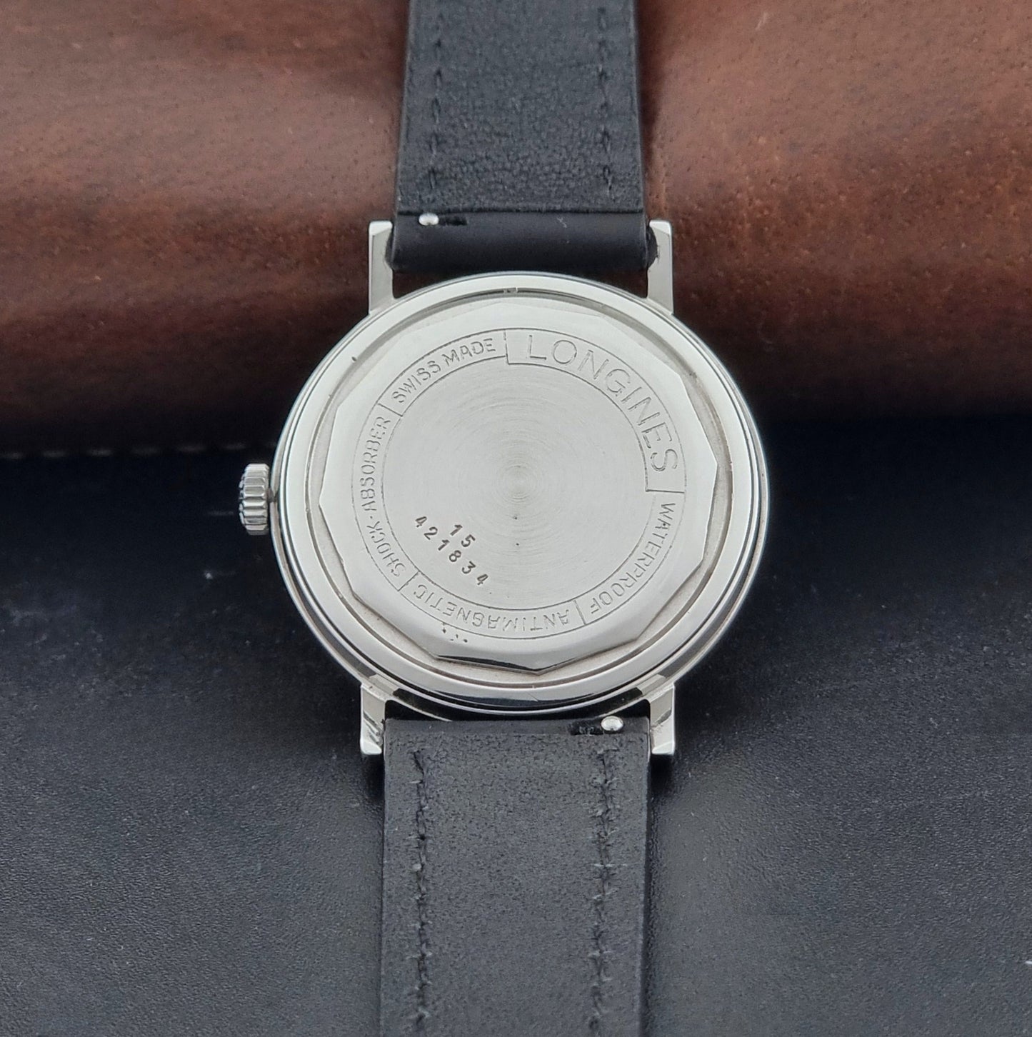 Vintage Longines 7839-5 watch with a black leather strap on a dark gray background case back view