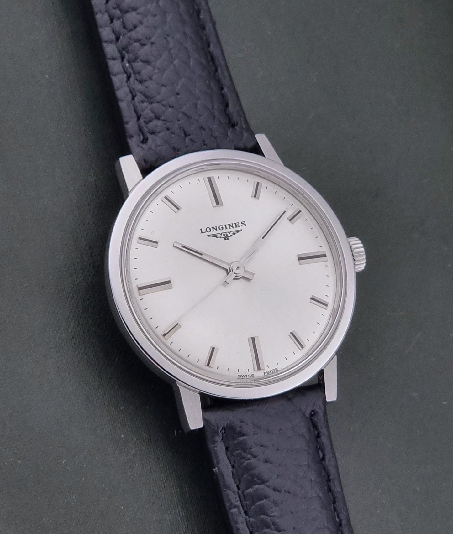 Vintage Longines 8319 Wristwatch with a black leather strap on a dark background front view
