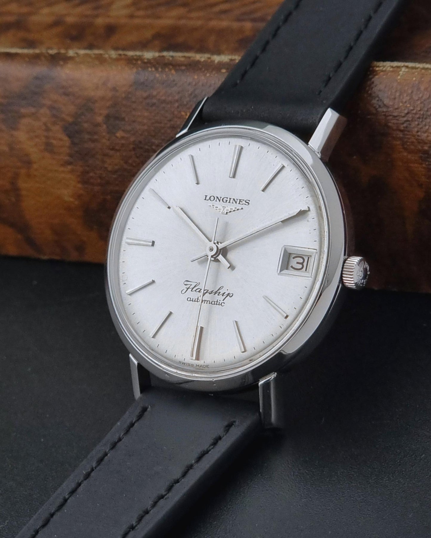 Vintage Longines Flagship watch with black leather strap on a dark surface