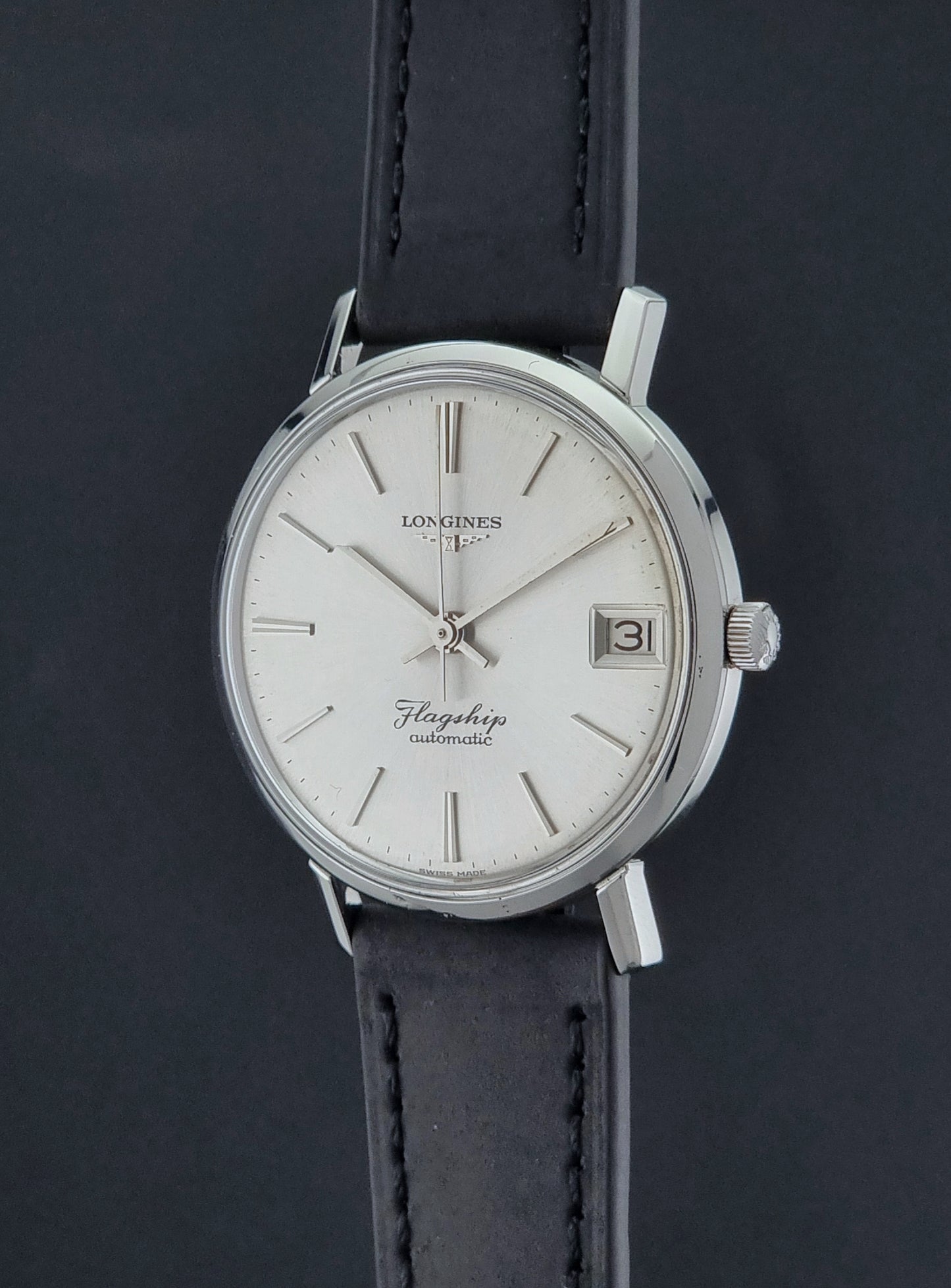 Vintage Longines Flagship watch with a silver dial and black leather strap on a dark background