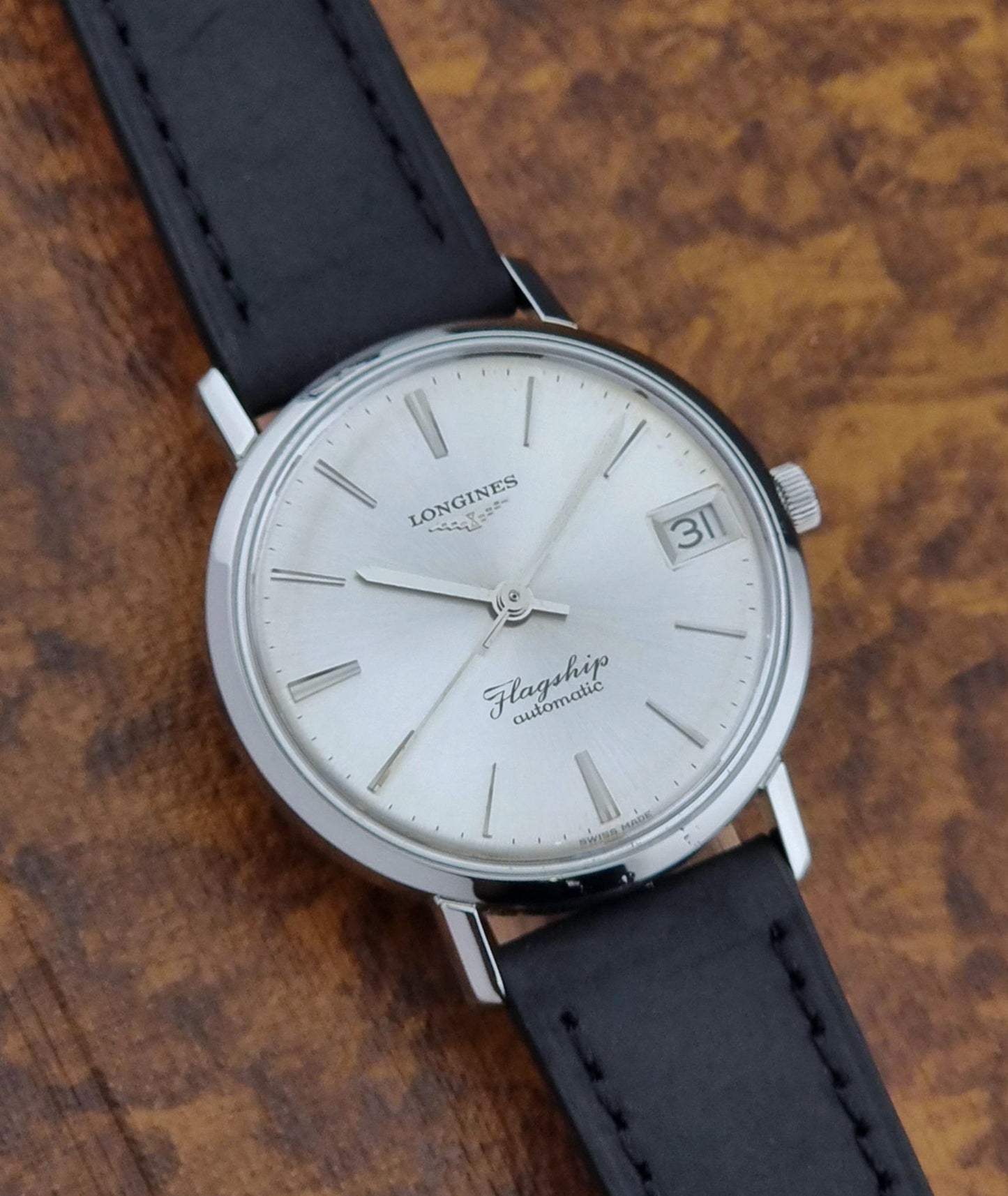 Longines watch with black leather strap on a wooden surface