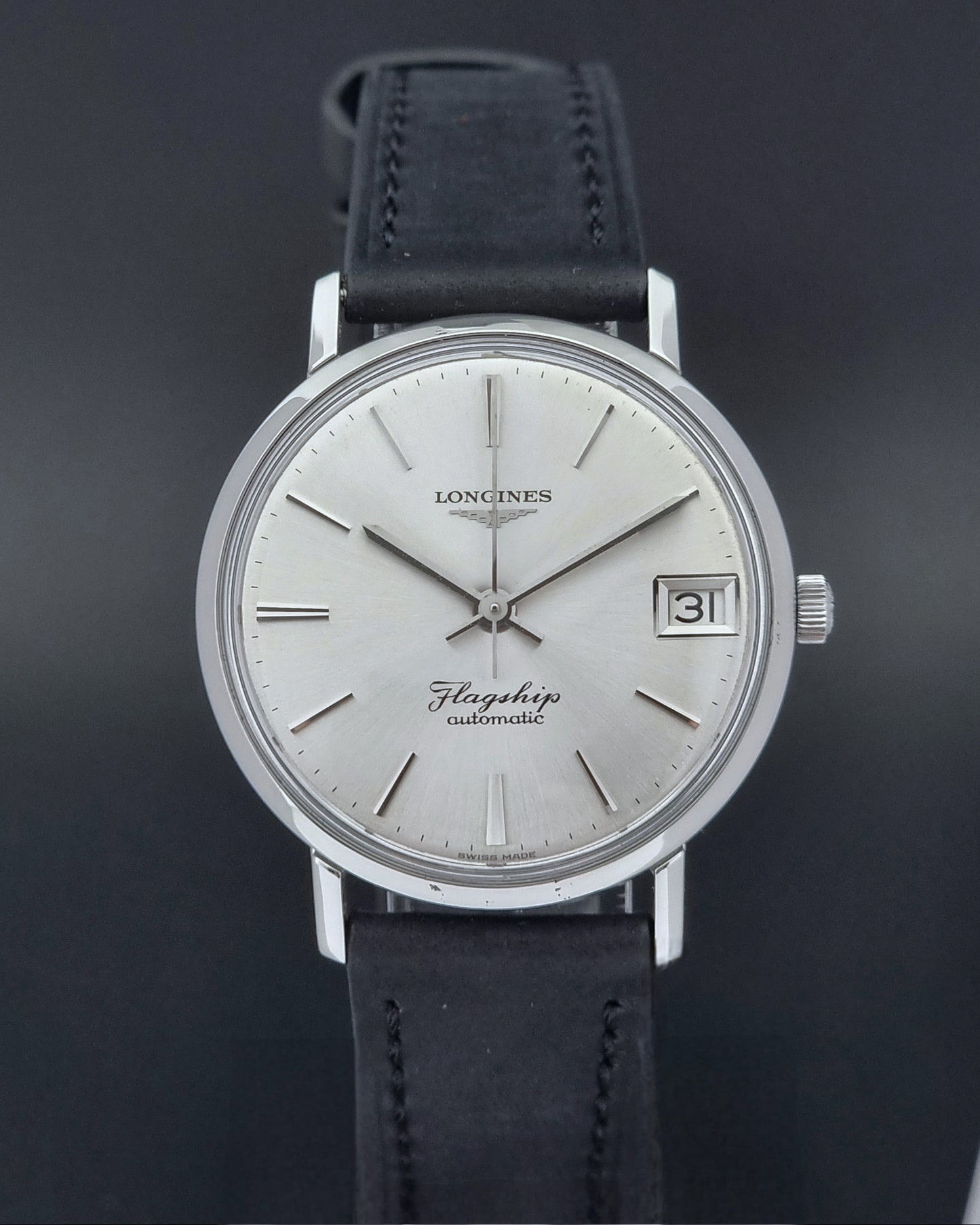 Front of a Vintage Longines Flagship watch with black leather strap on a dark background