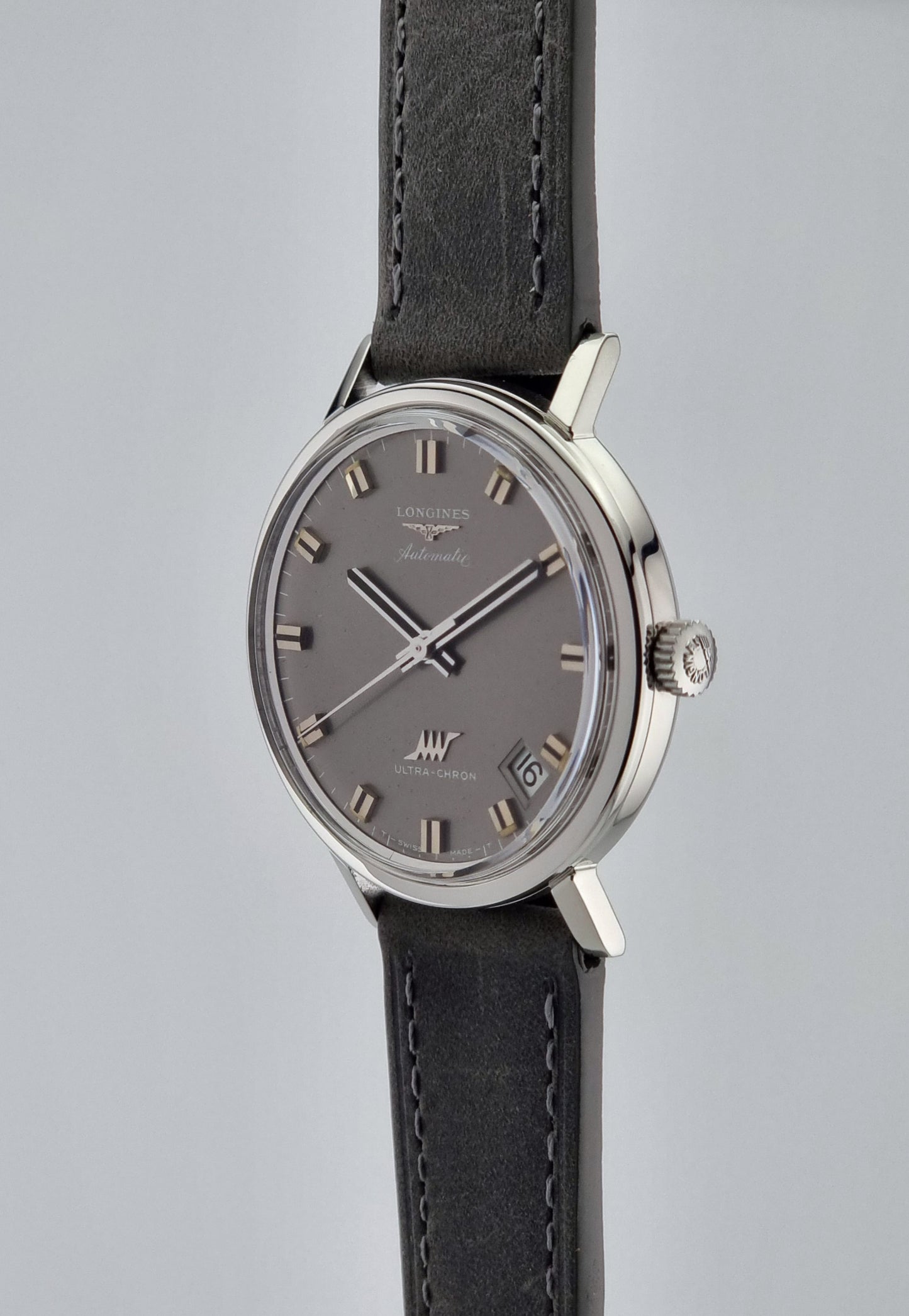 Vintage Longines Ultra-Chron Wristwatch with gray dial and grey leather strap on a light gray background