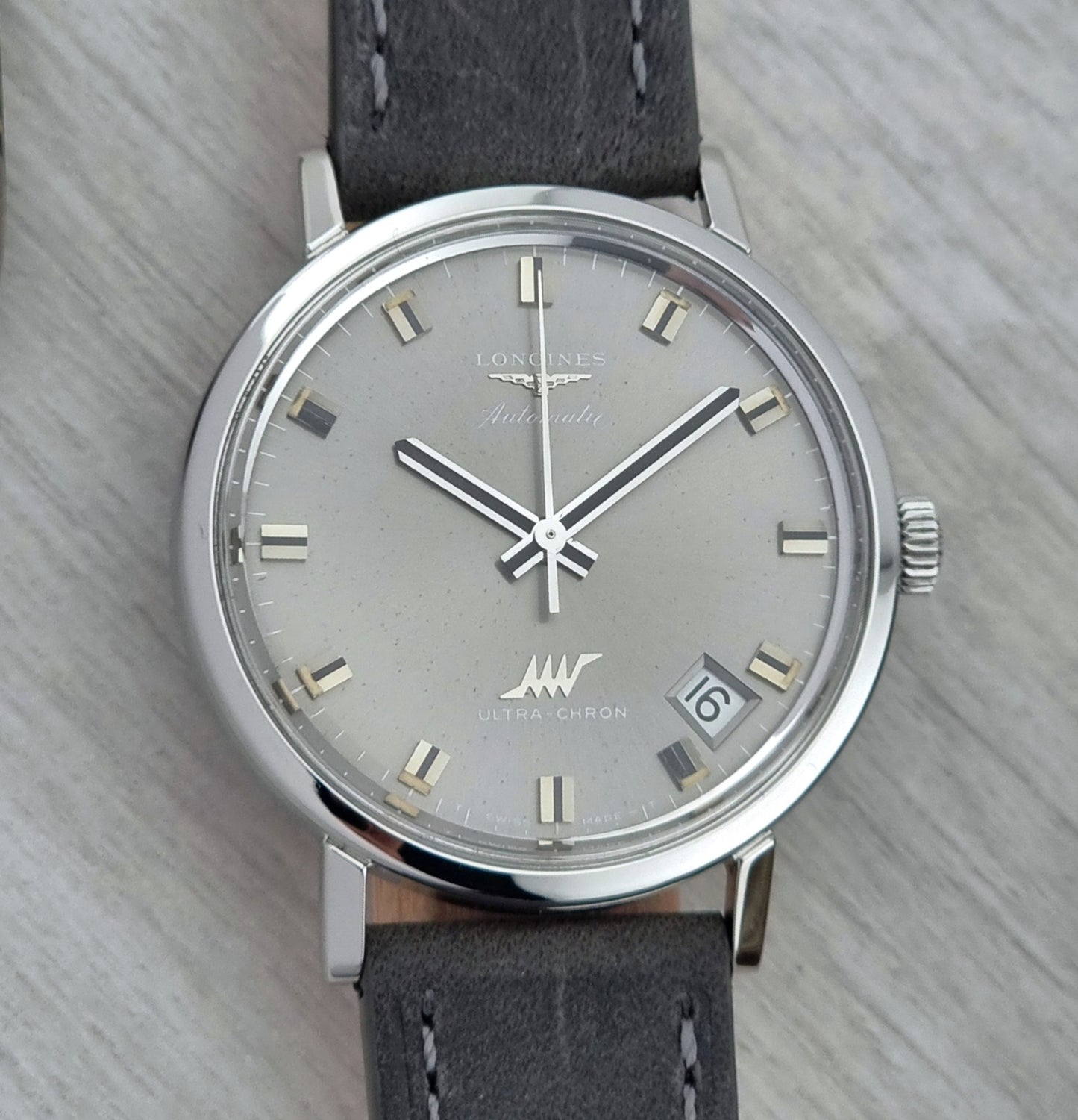 Vintage Longines Ultra-Chron Watch with gray strap and silver case on a light gray background