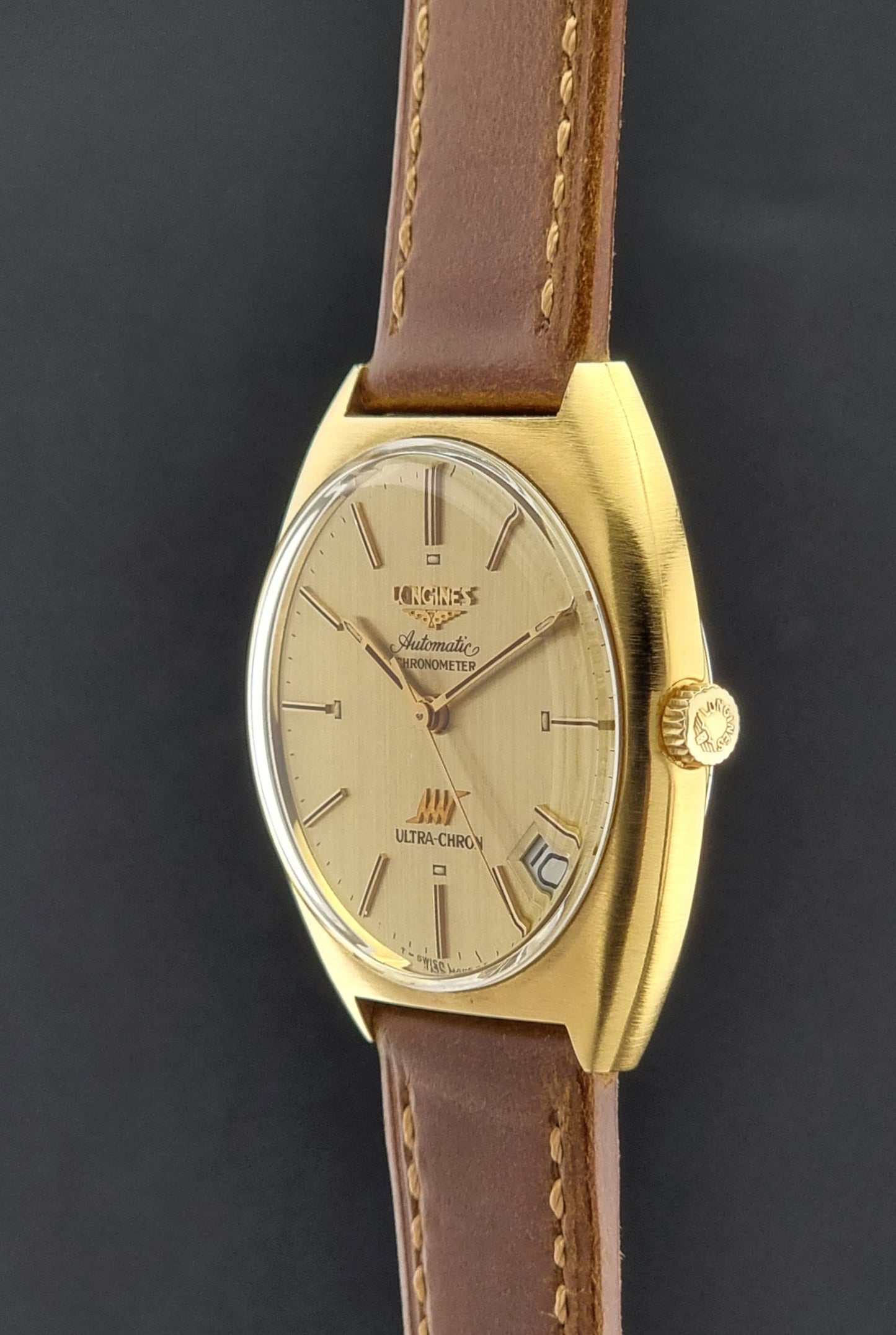 Vintage Longines Gold watch with brown leather strap on a dark background