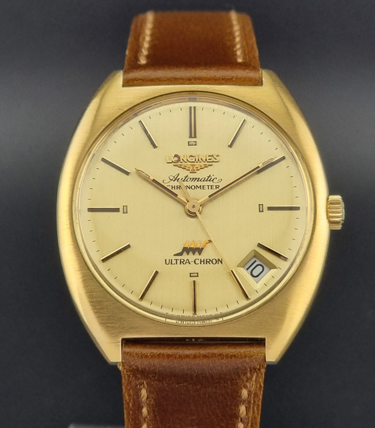 Vintage Longines Gold wristwatch with brown leather strap on a dark background