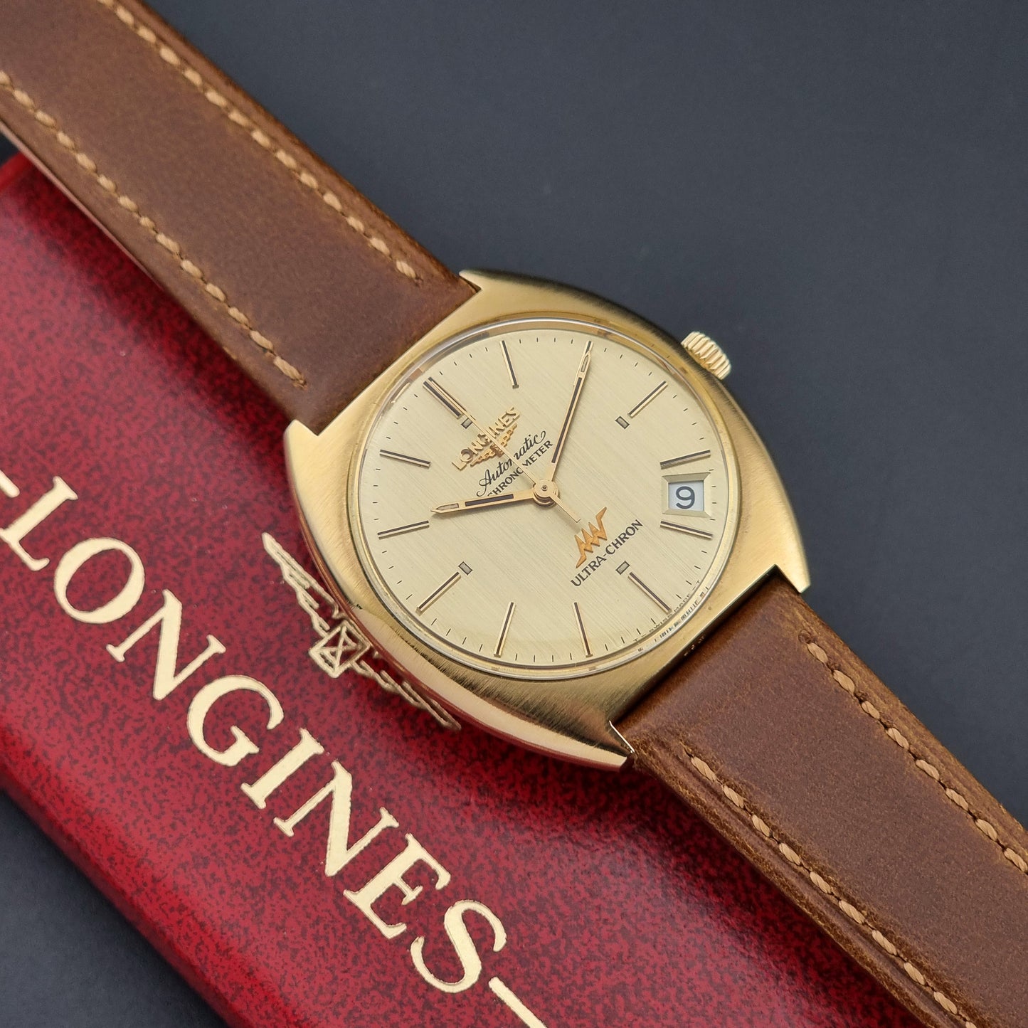 Vintage Longines Gold wristwatch with brown leather strap on a Longines box