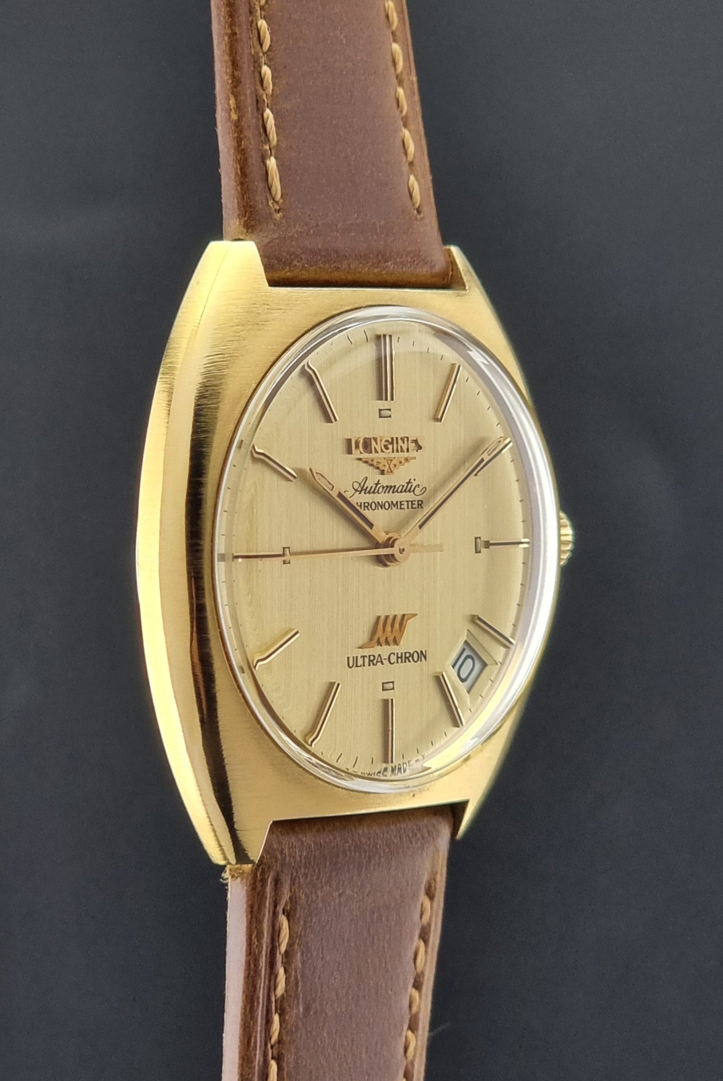 Vintage Longines Gold watch with brown leather strap on a dark background