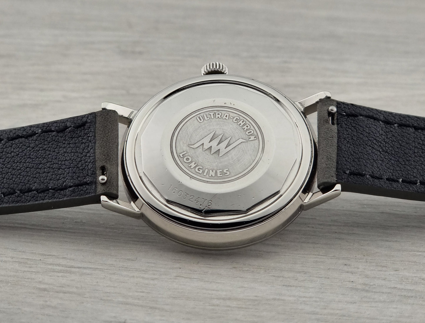 Close-up of a watch with a visible brand logo on a gray surface