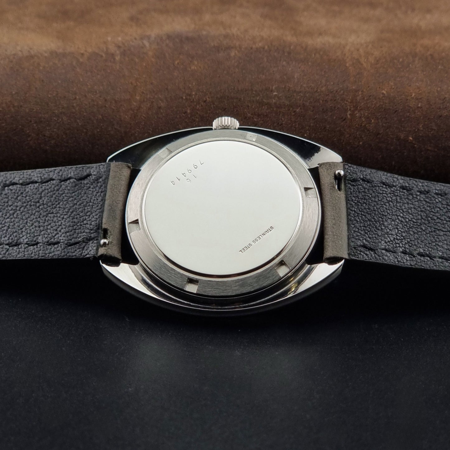 Vintage Longines wristwatch ULTRA-CHRON 8317 with a grey leather strap on a dark background case back view