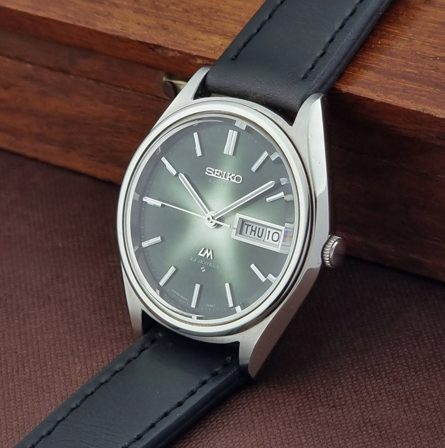 Seiko watch with black leather strap on a wooden surface