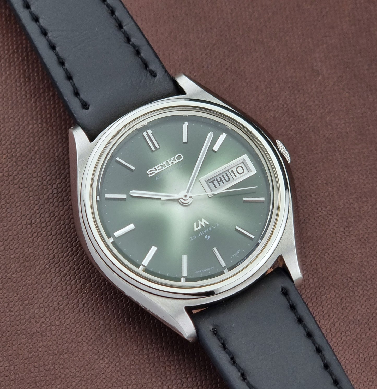 Seiko watch with a black leather strap on a brown background