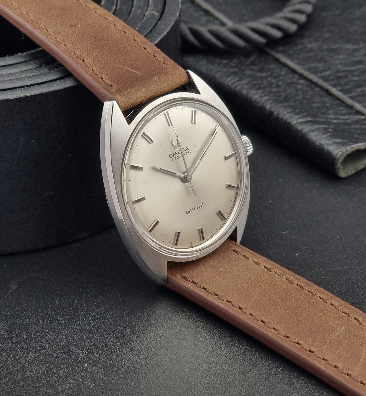 Vintage Omega watch with brown leather strap on a dark textured surface