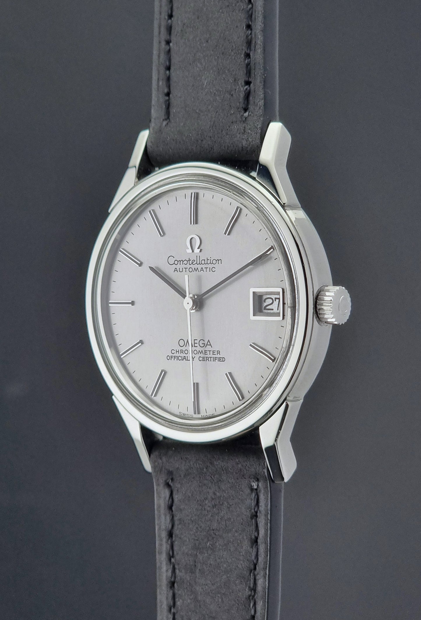 Omega watch with silver case and black leather strap on a dark background