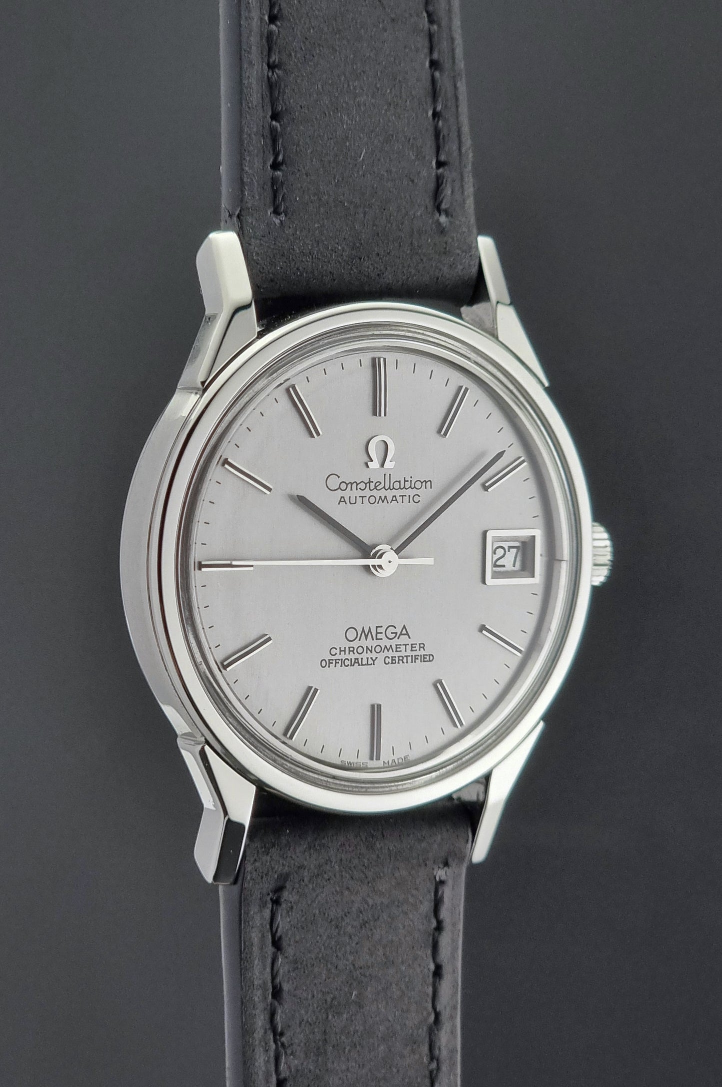 Omega watch with silver dial and black leather strap on a dark background