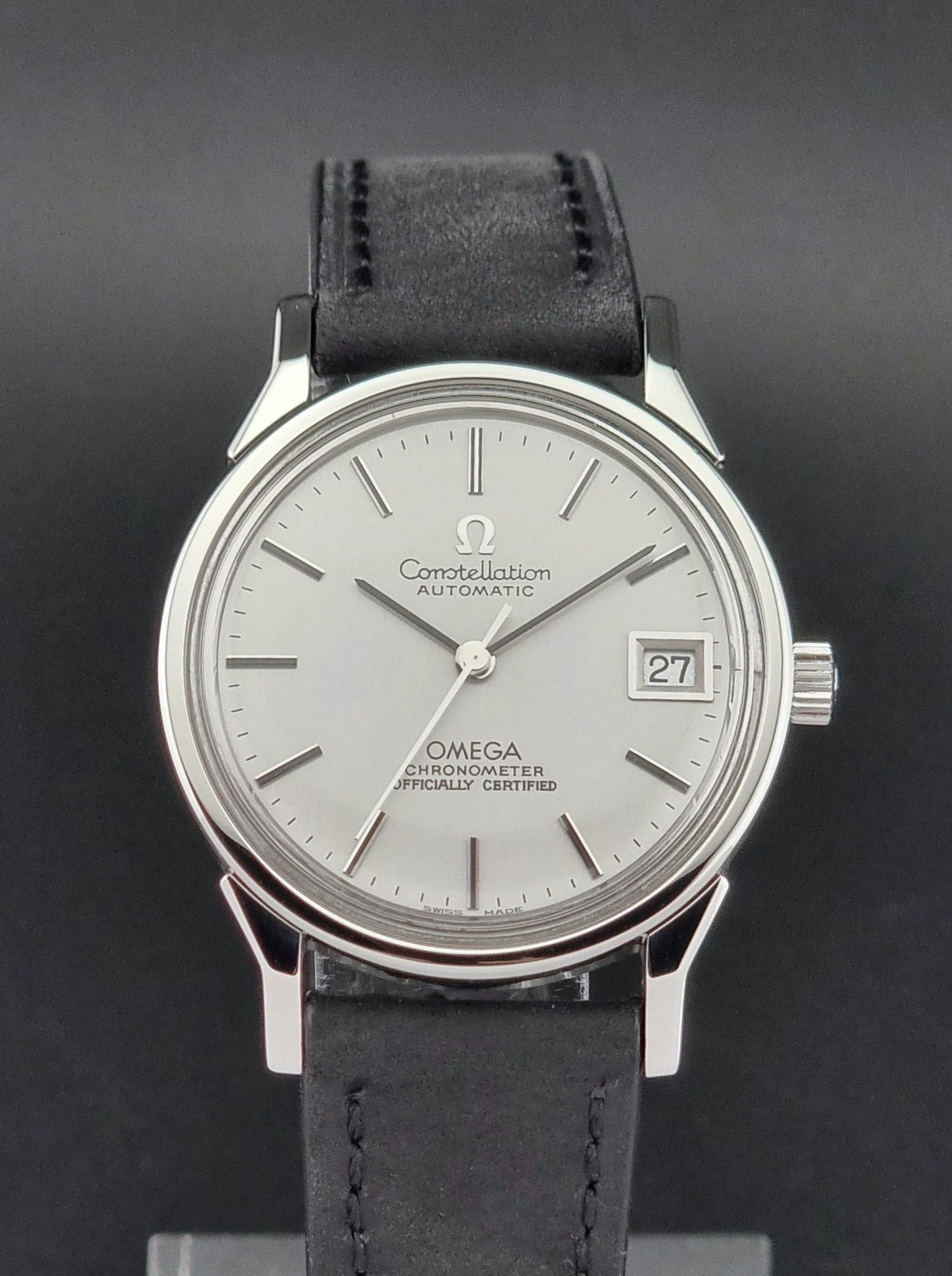 Omega watch with silver dial and black leather strap on a dark background