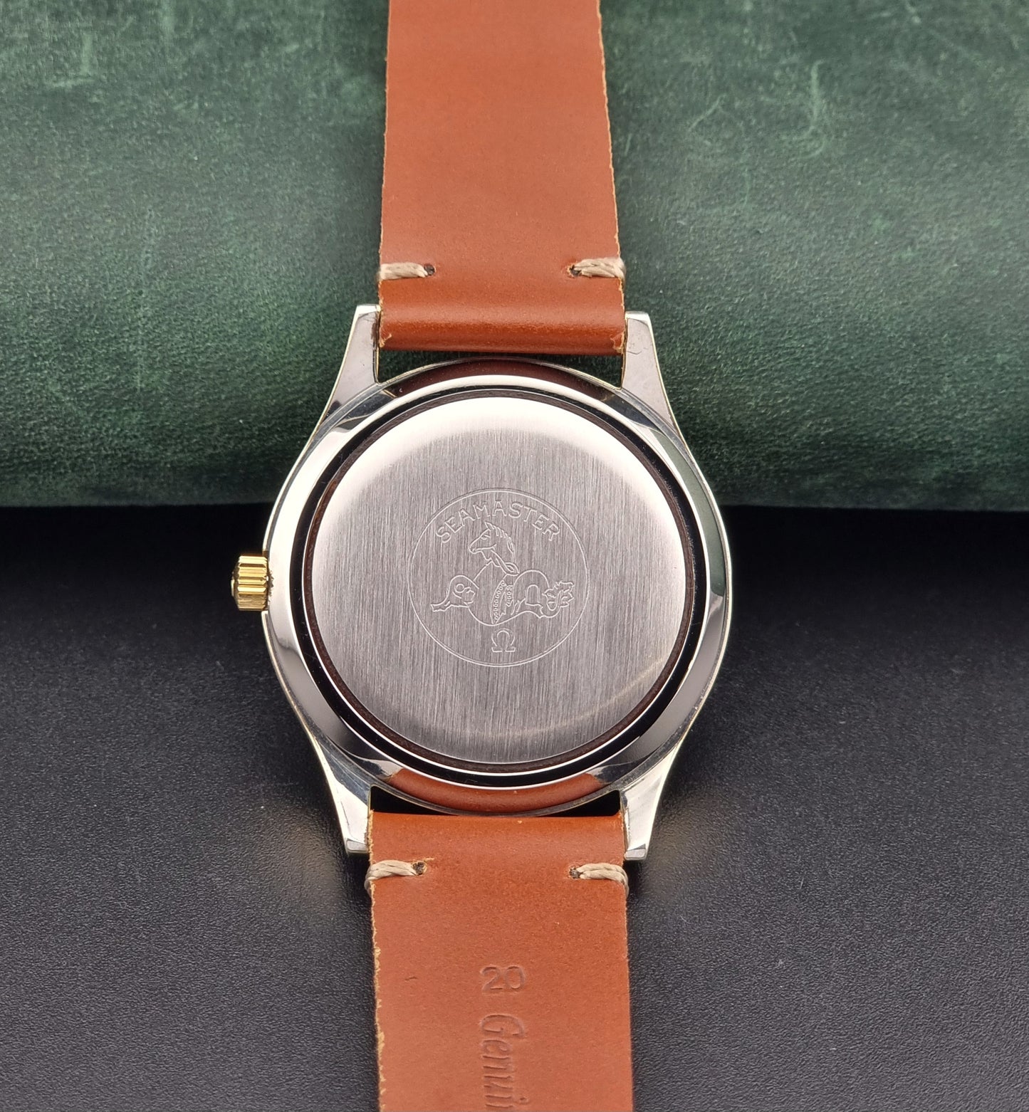 Back view of a Vintage Omega Seamaster Cosmic 2000Watch with brown leather strap and visible brand logo on a dark surface