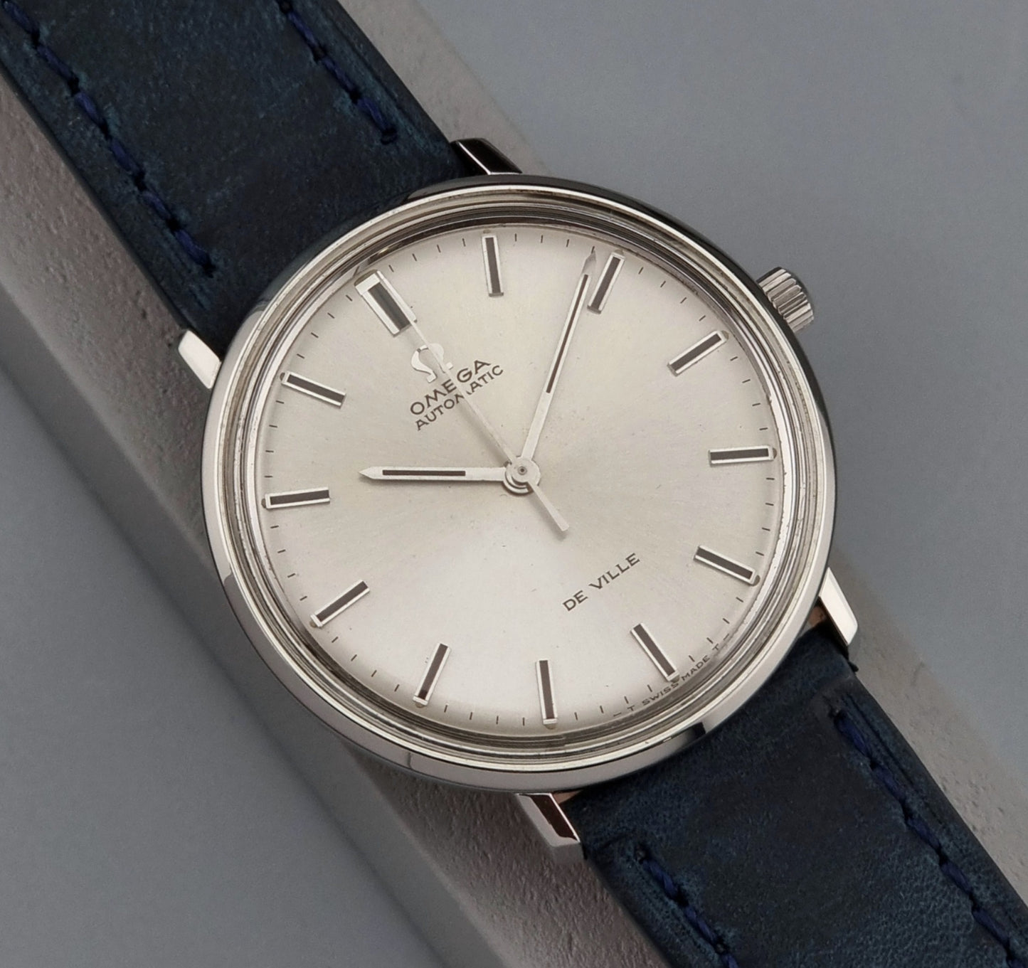 Vintage Omega De-Ville watch with blue leather strap on a gray background