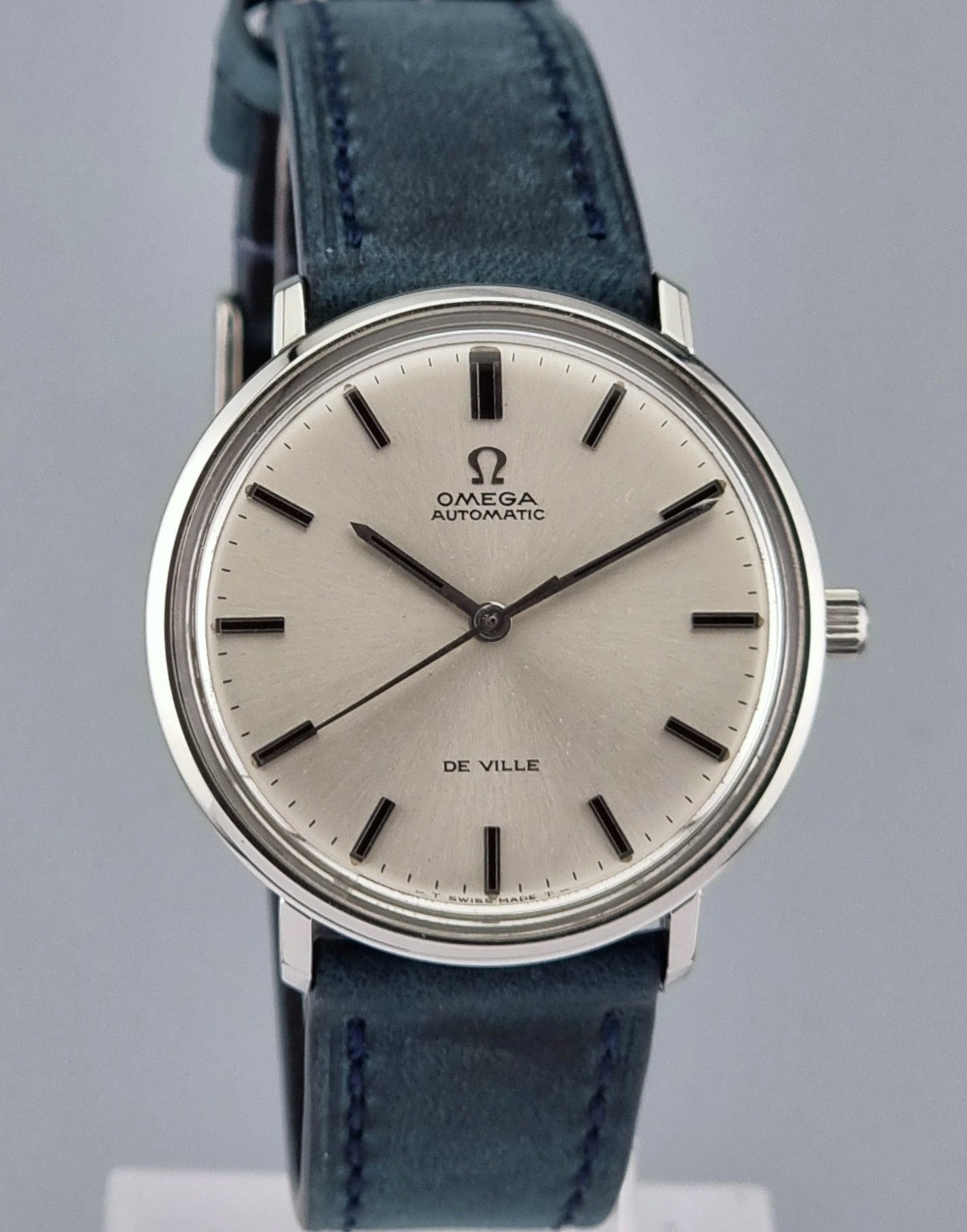 Vintage Omega De-Ville watch with blue leather strap on a gray background