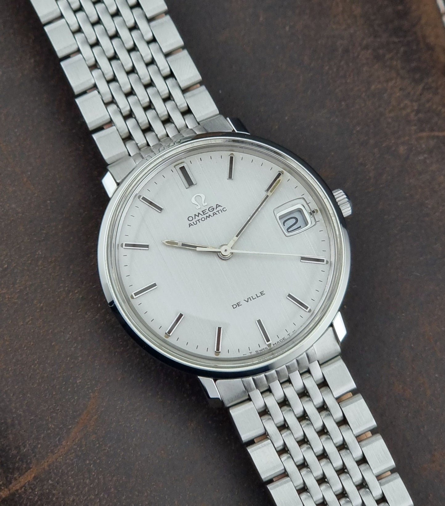 Vintage Omega De Ville watch on a dark brown leather background