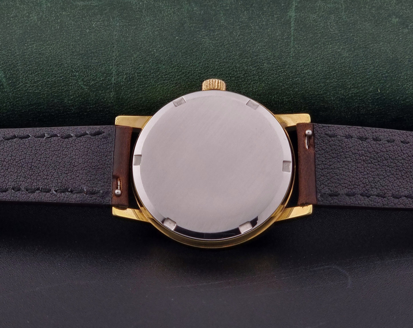 Vintage Omega Wristwatch Geneve 136.0098 with brown leather strap on a green surface case back view