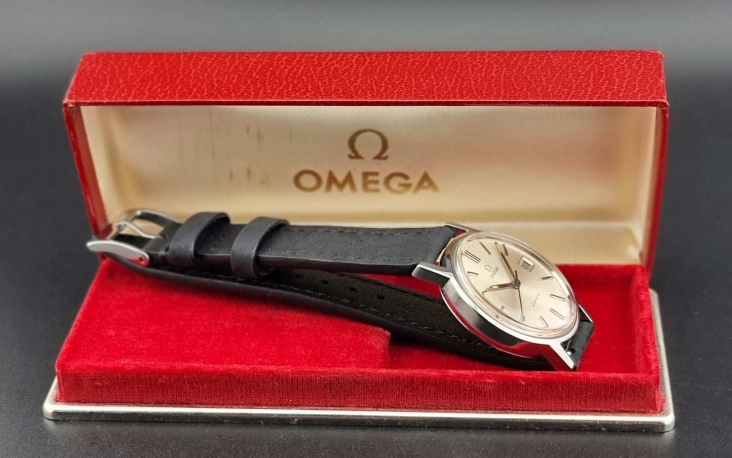 Vintage Omega watch in a red Omega box on a gray background