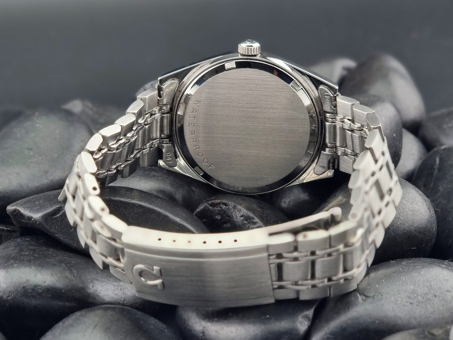 Back view of a Vintage Omega Geneve watch on dark stones