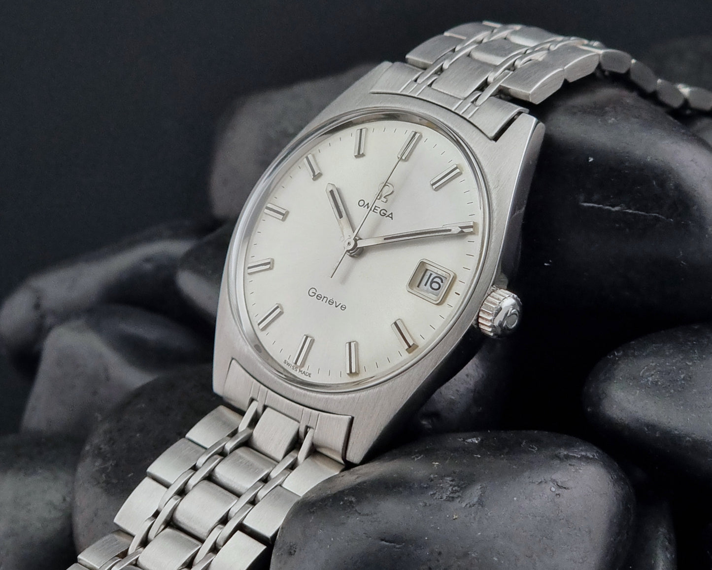 Side view of a Vintage Omega Geneve watch on a dark stone surface