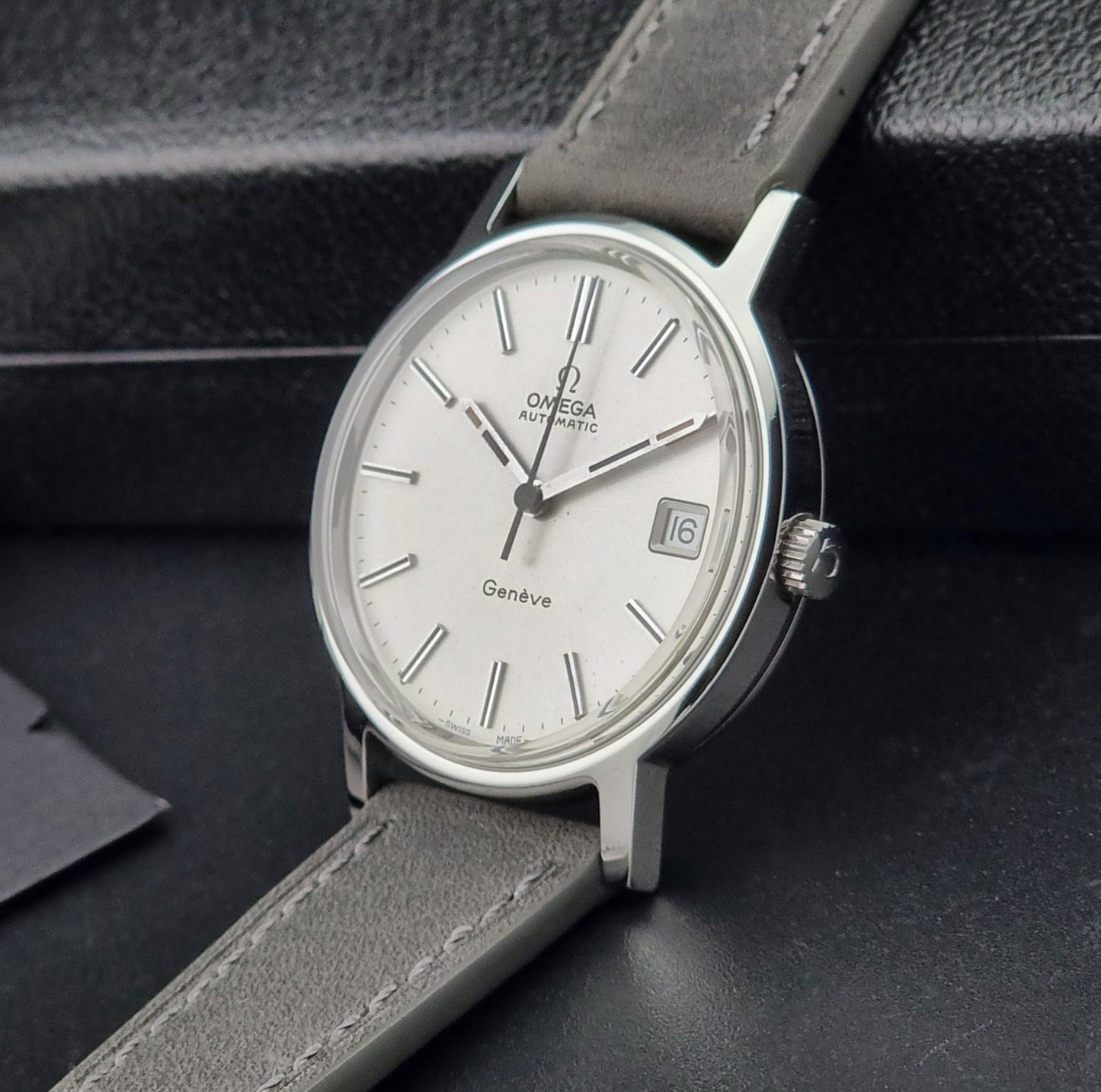 Vintage Omega watch with gray leather strap on a dark background