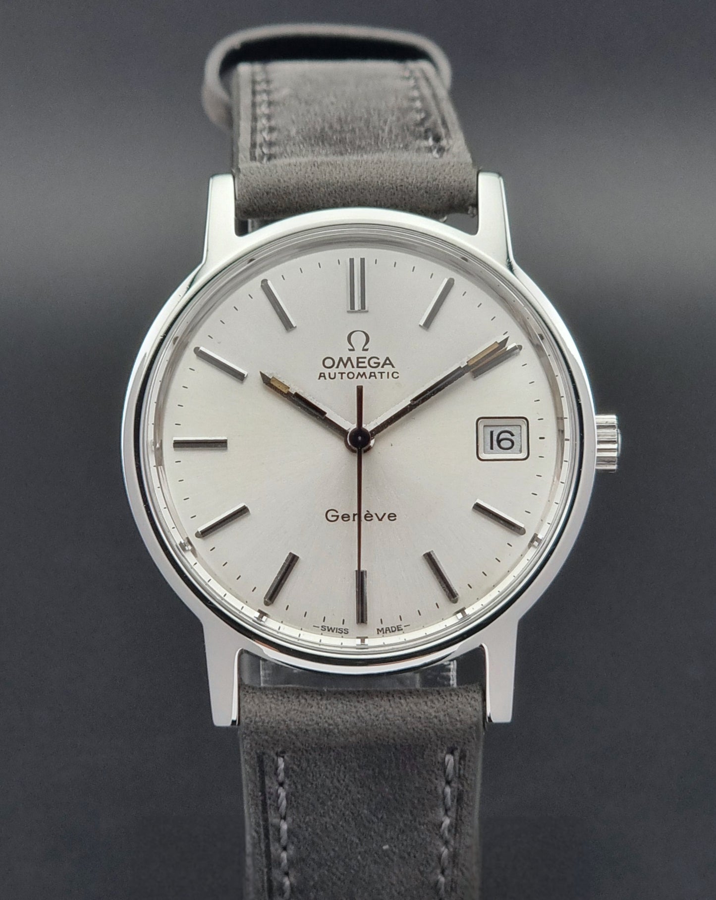 Vintage Omega Genève watch with silver case and white dial on a dark background