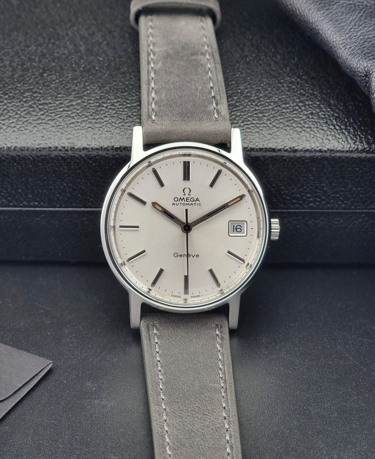 Vintage Omega watch with gray strap on a dark textured surface
