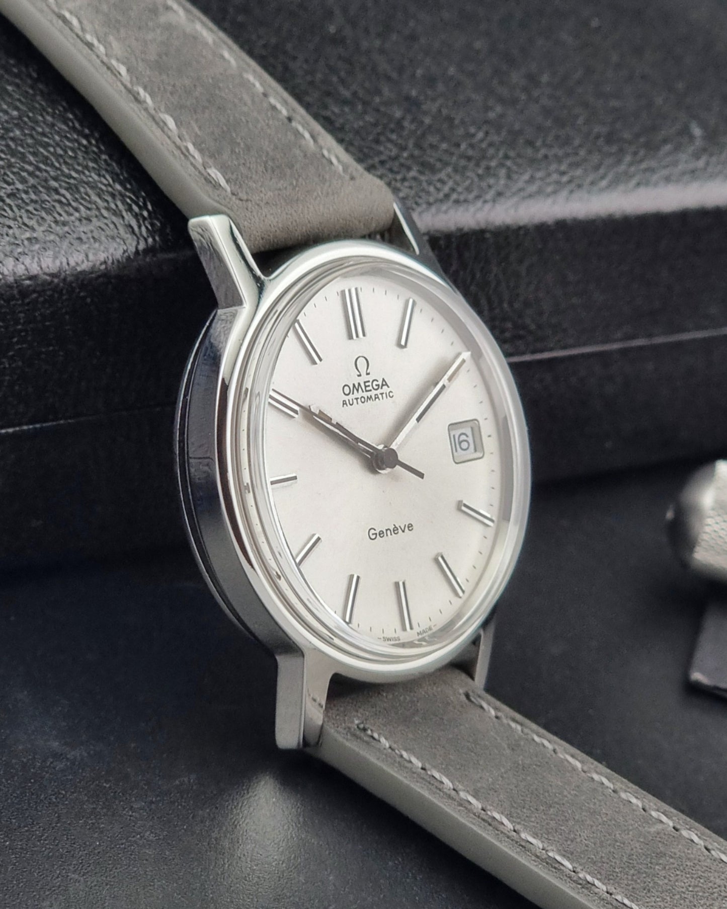 Vintage Omega watch with a silver case and white dial on a dark background