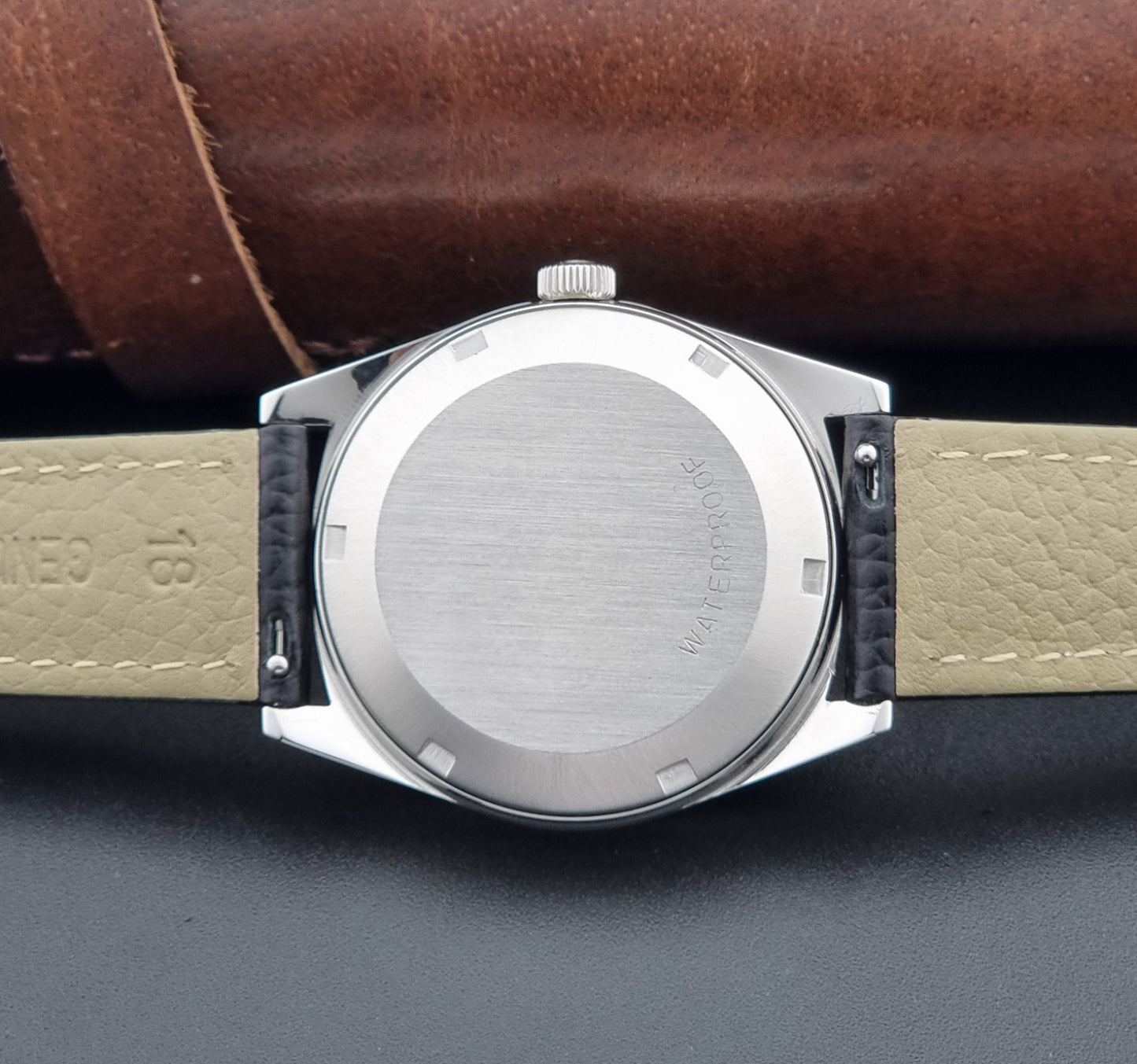 Vintage Omega Wristwatch a Geneve 166.041 with black leather strap on a dark surface case back view