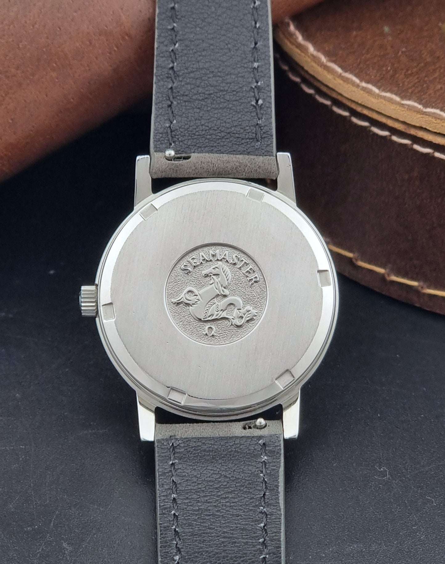 Vintage Omega Wristwatch Seamaster 136.0099 with a grey leather strap on a dark surface case back view