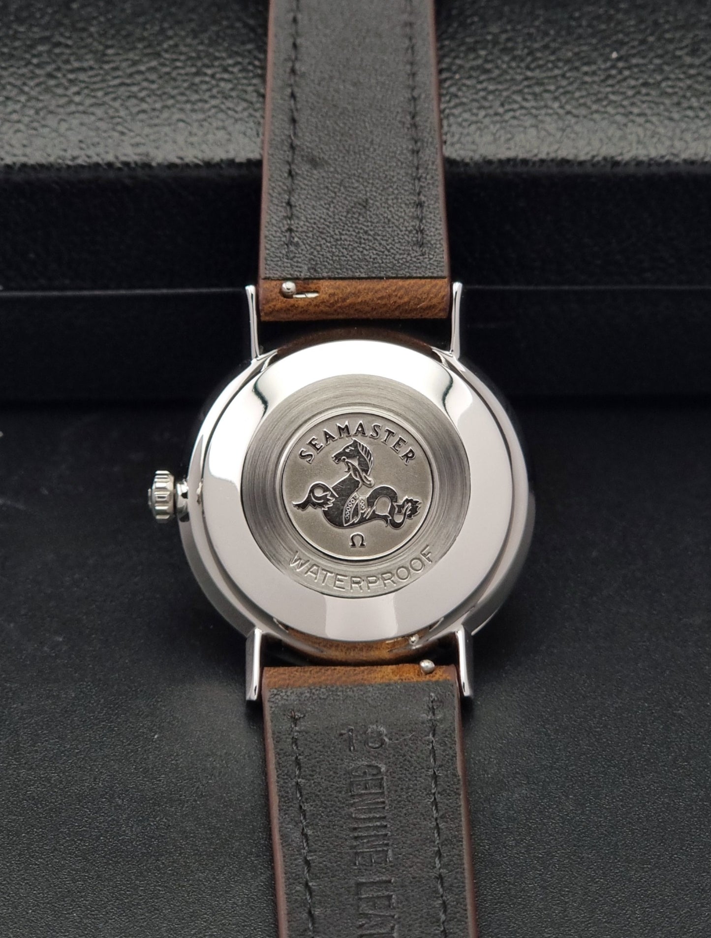 Vintage Omega Seamaster 14770 watch with a brown leather strap on a dark background case back view
