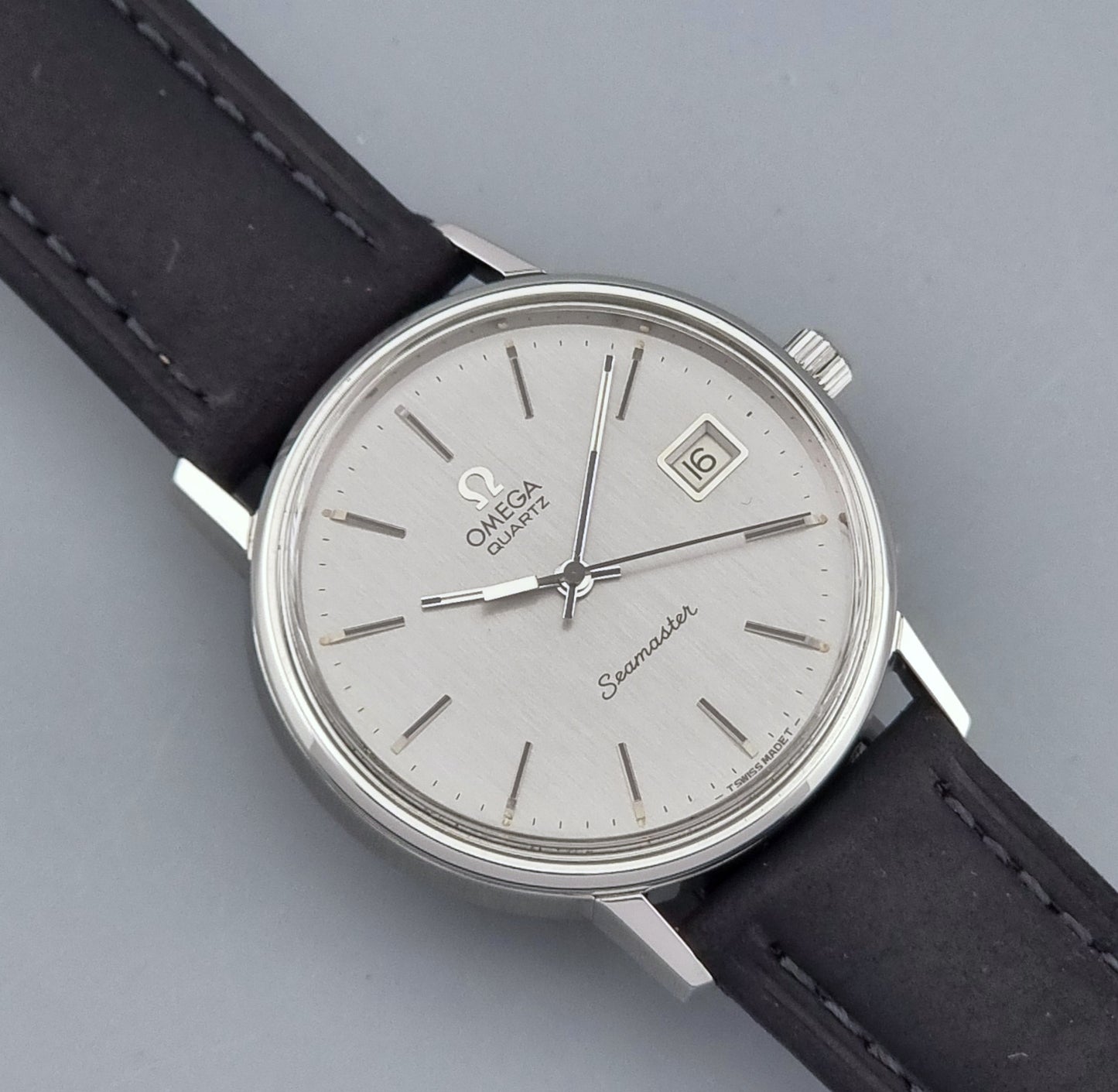 Vintage Omega Quartz Wristwatch Seamaster 196.0079 watch with a black strap on a gray background front view