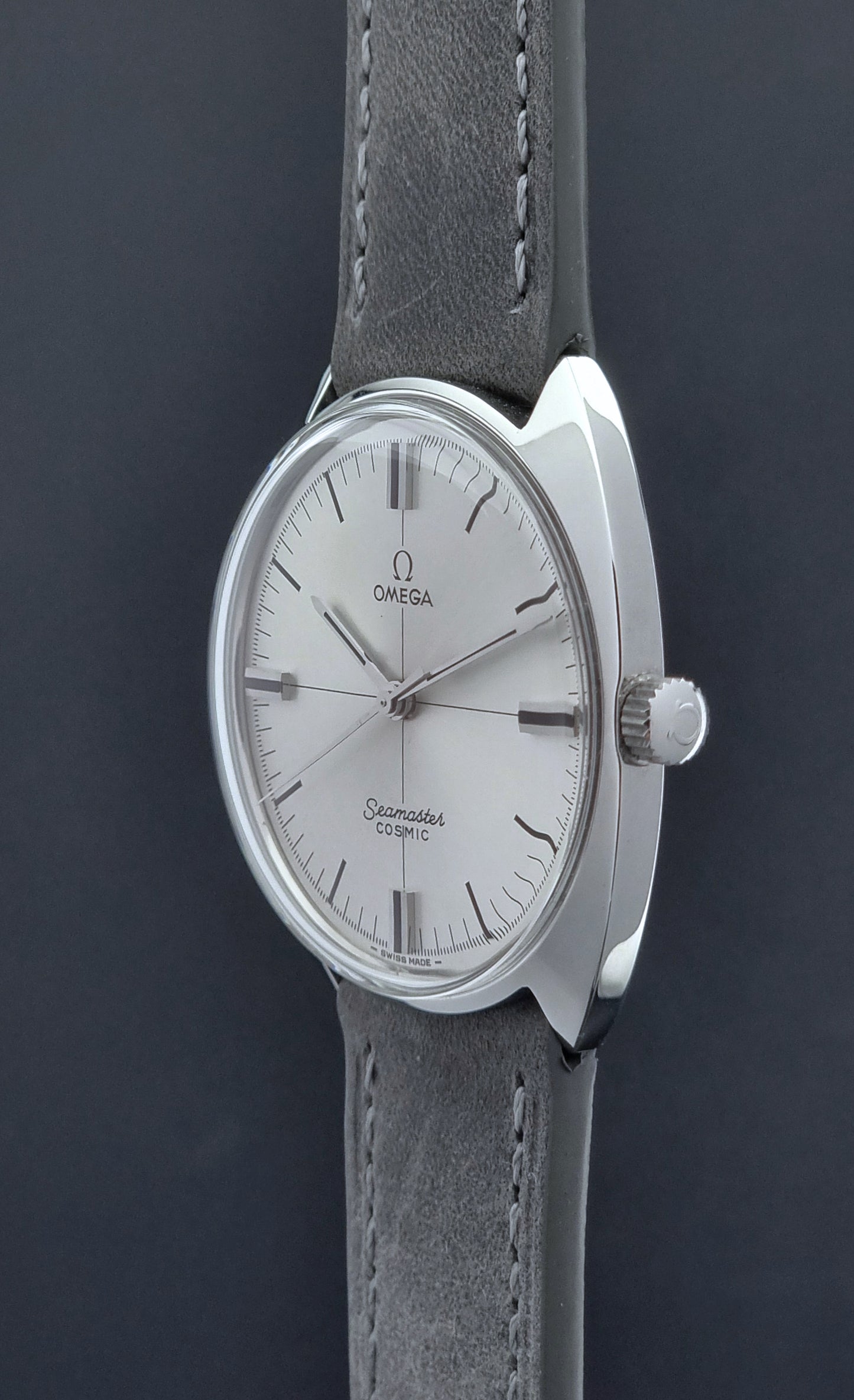 Omega watch with silver case and gray leather strap on a dark background crown side profile