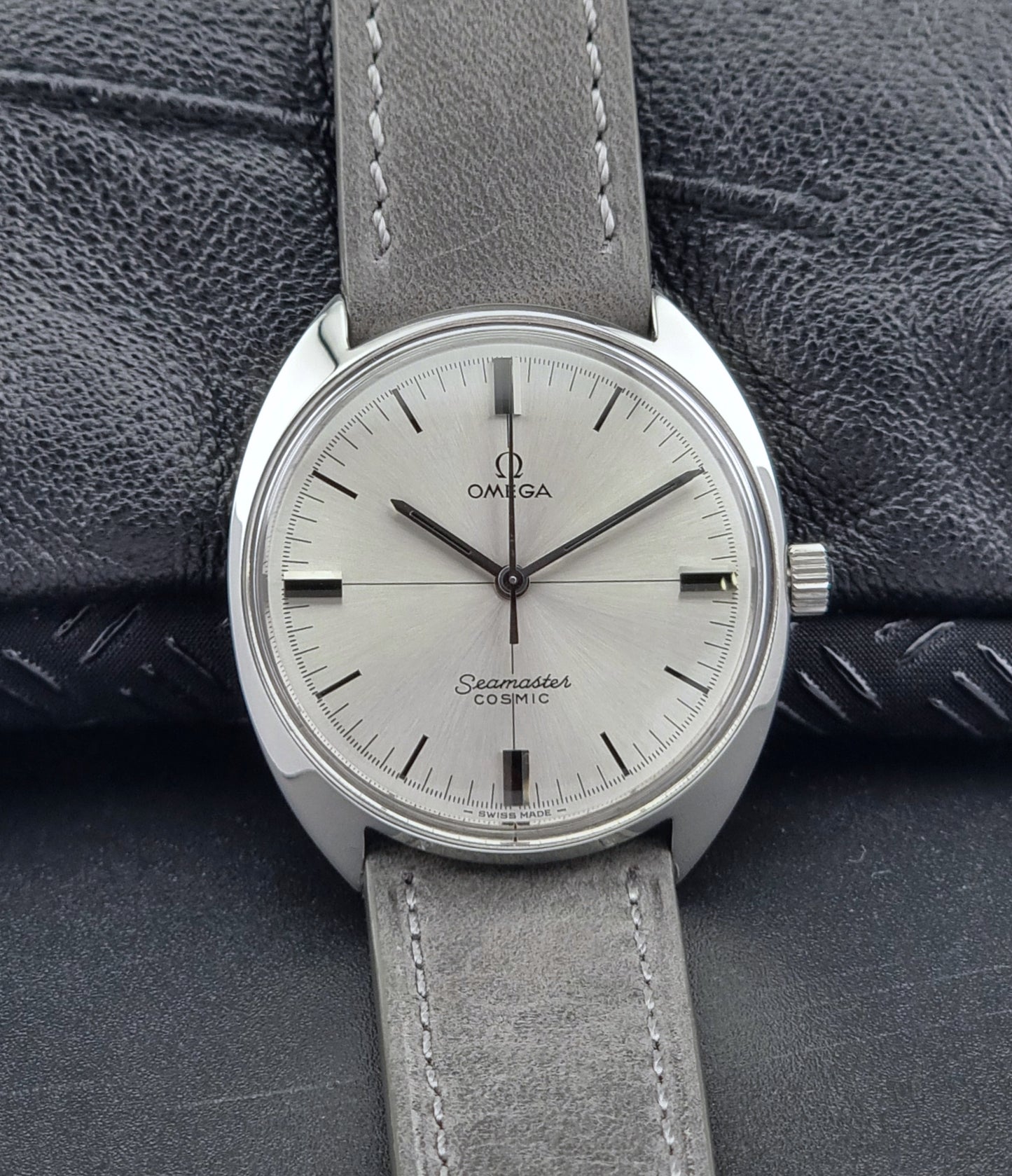 Omega Seamaster Cosmic watch with gray leather strap on textured surface