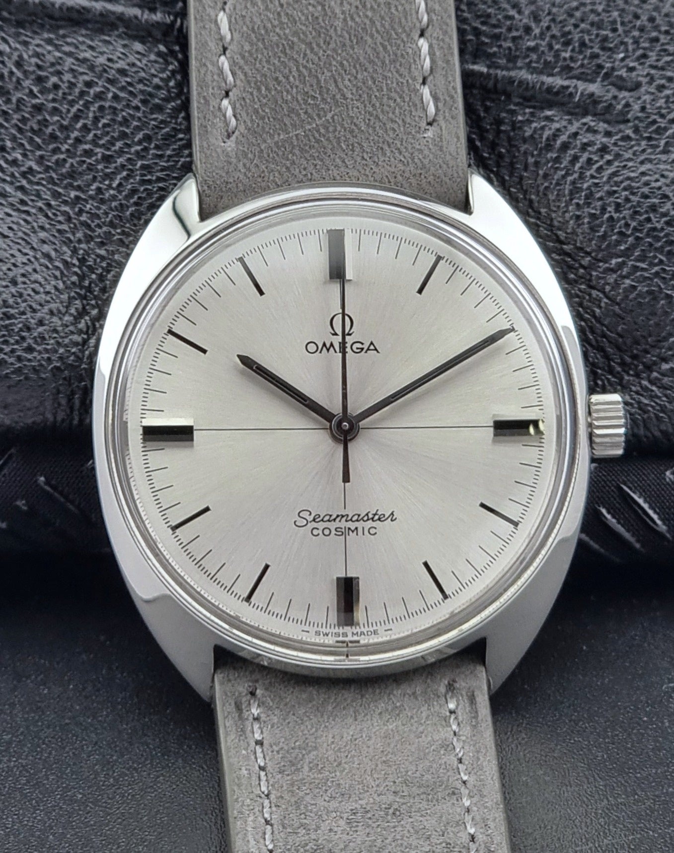 Omega Seamaster Cosmic watch with gray leather strap on a dark textured background front