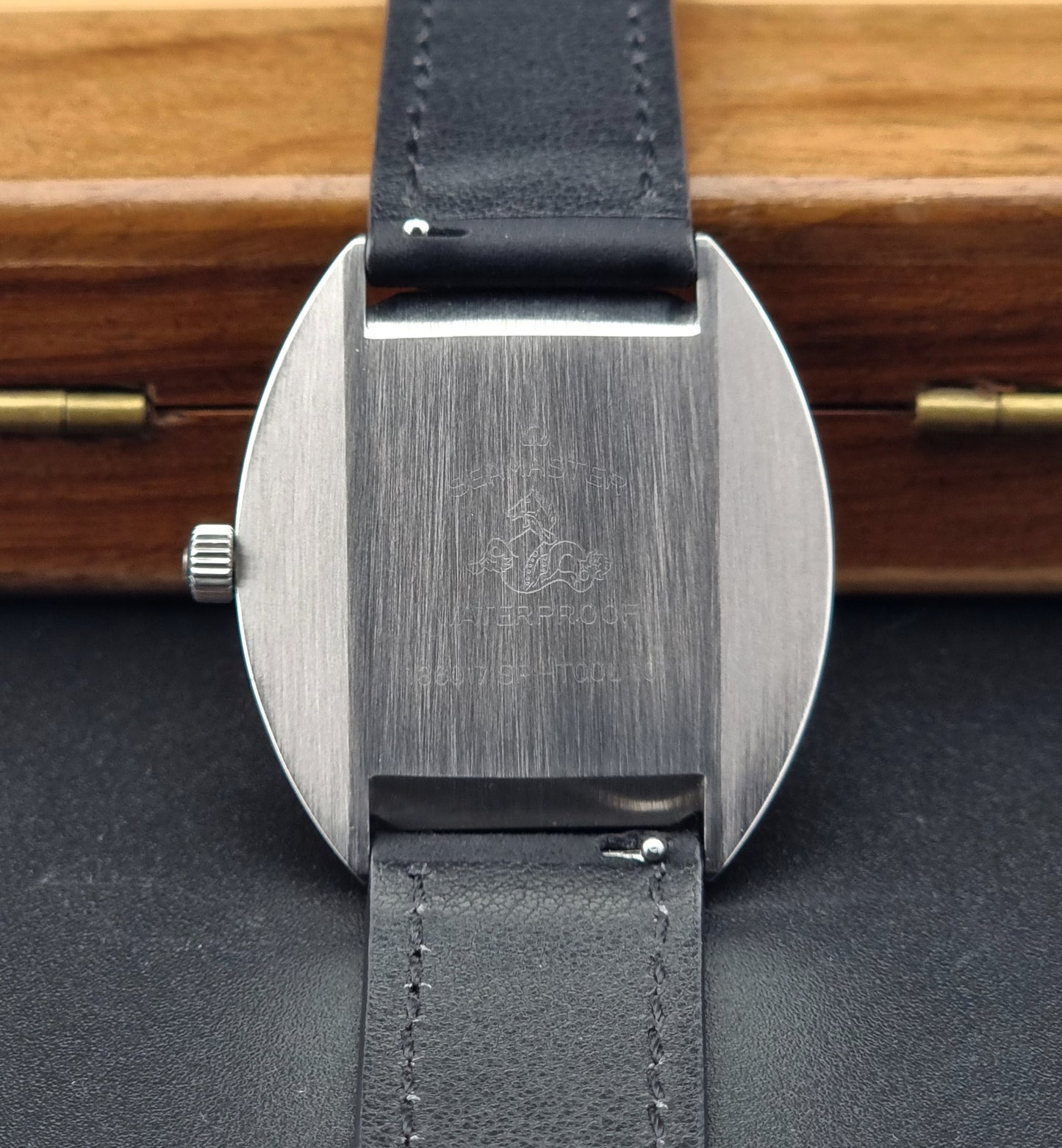 Omega Seamaster Cosmic 136.017 with black leather strap and metal case back on a wooden surface