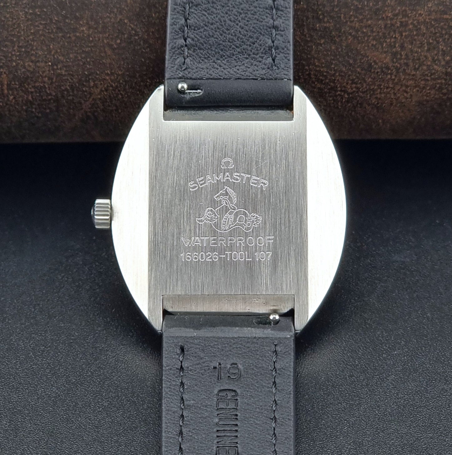 Close-up of the back of an Omega Seamaster watch with 'Seamaster' branding on a dark background