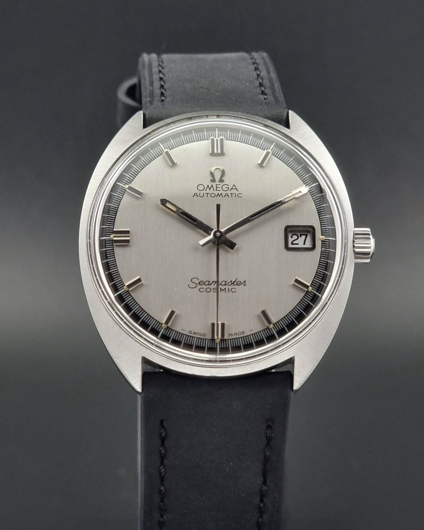 Vintage Omega Seamaster Cosmic watch with silver dial and black leather strap on a dark background