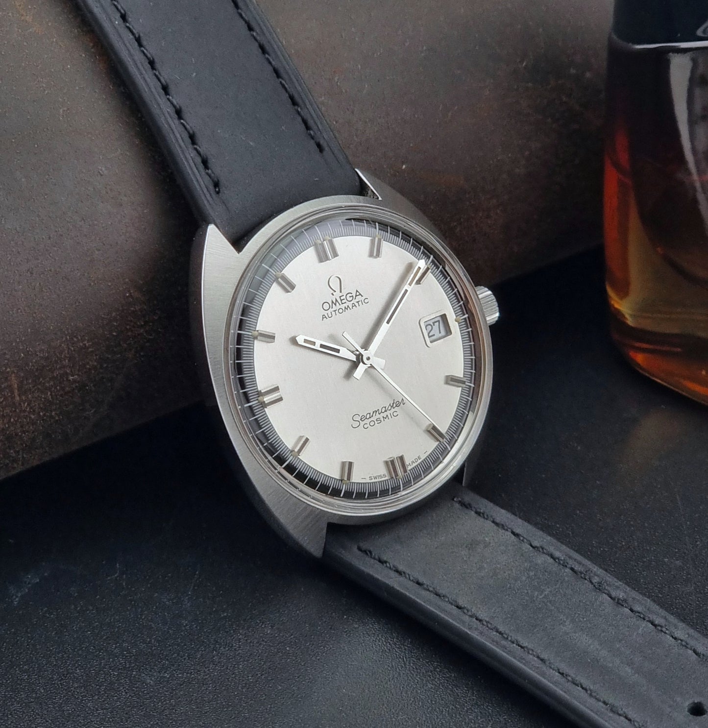 Vintage Omega Seamaster Cosmic watch with black leather strap on a dark surface