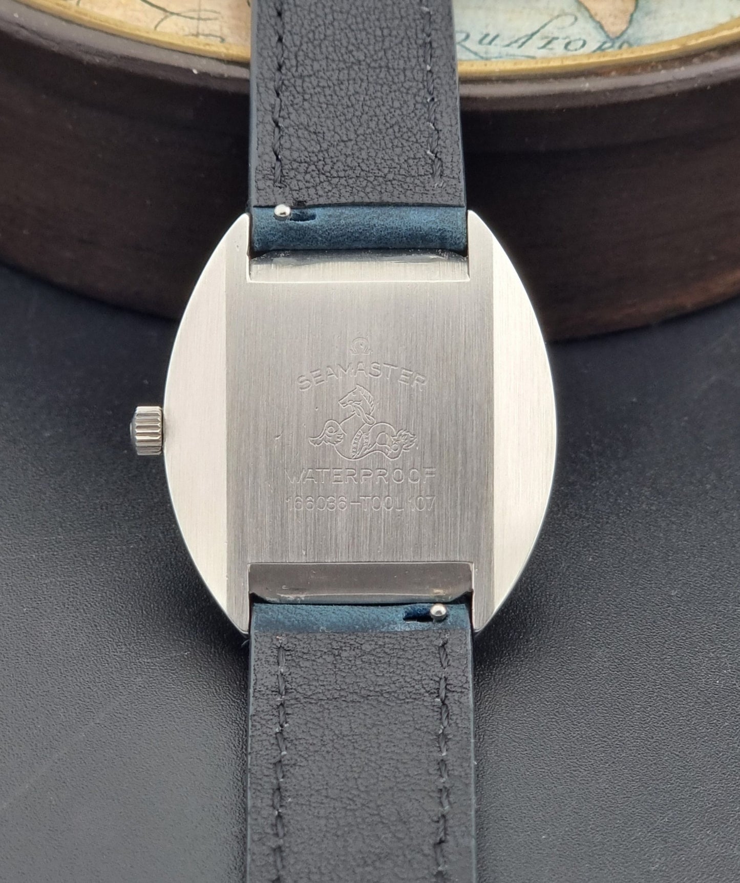 Vintage Omega Wristwatch 166.036 Seamaster Cosmic with blue leather strap on a dark surface case back view