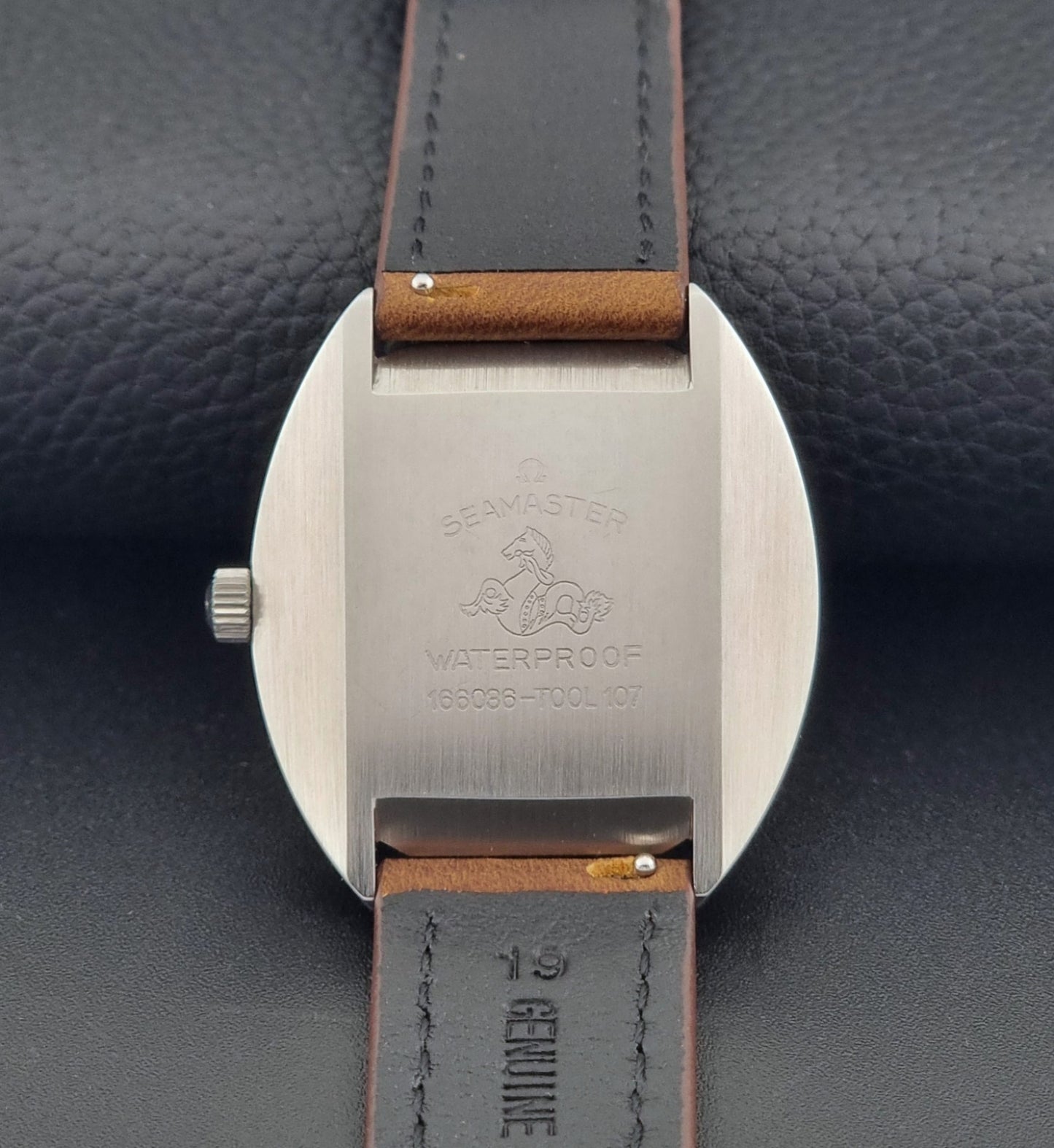 Vintage Omega Seamaster Cosmic 166.036 wristwatch with brown leather strap on a dark background case back view