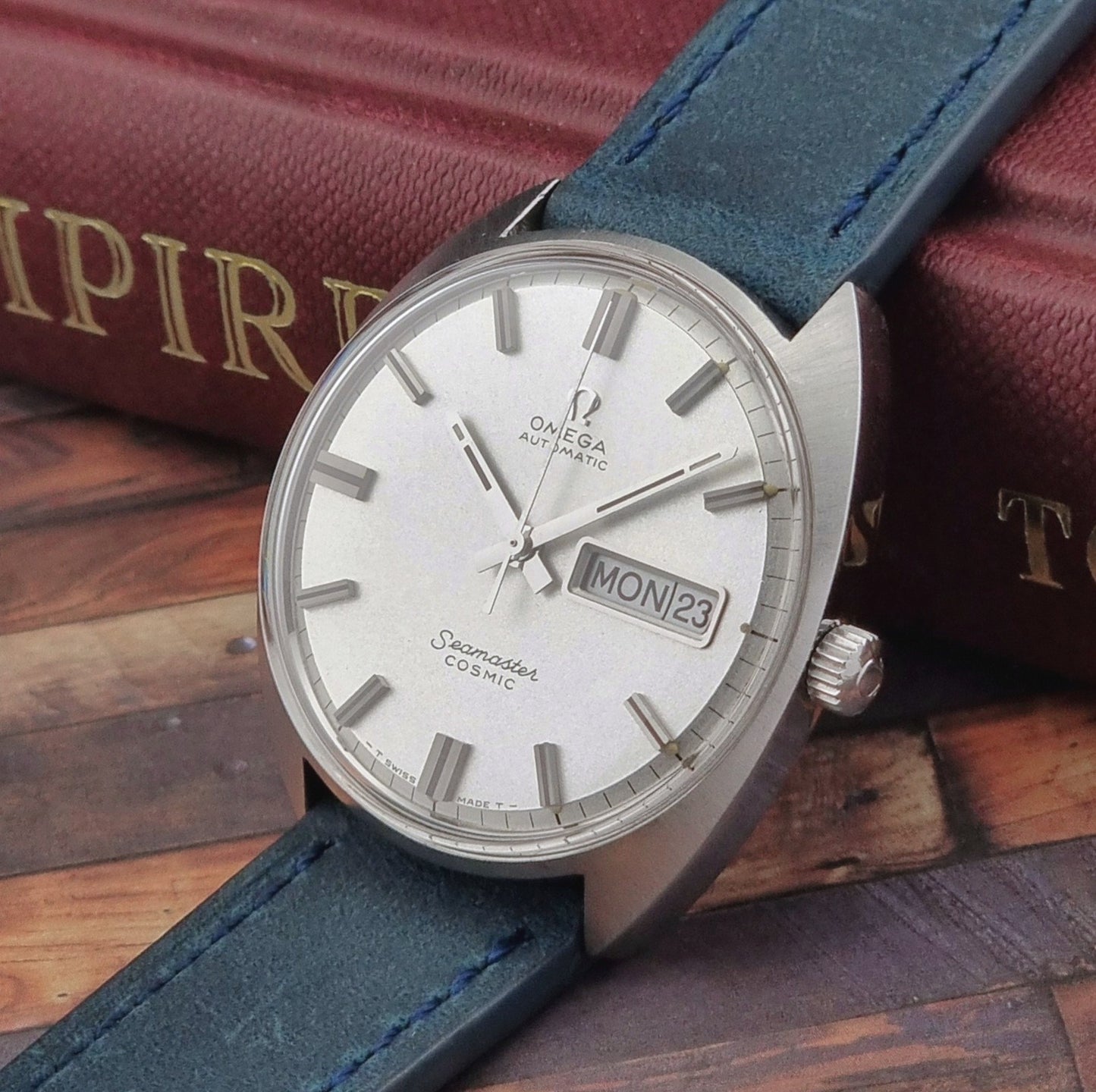 Vintage Omega Seamaster Cosmic watch with blue strap on a wooden surface