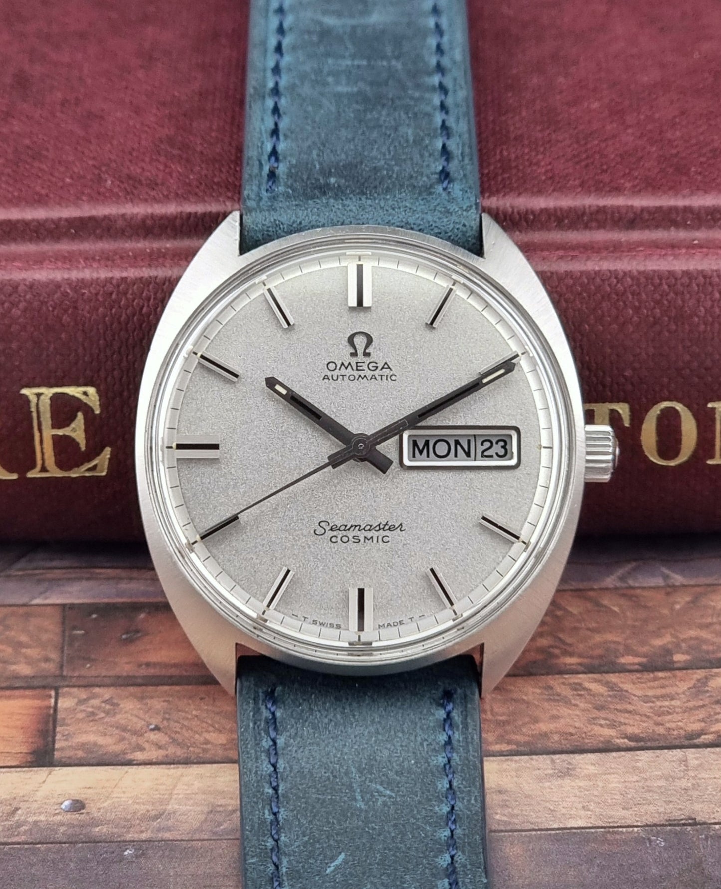 Vintage Omega Seamaster Cosmic watch with blue strap on a wooden surface
