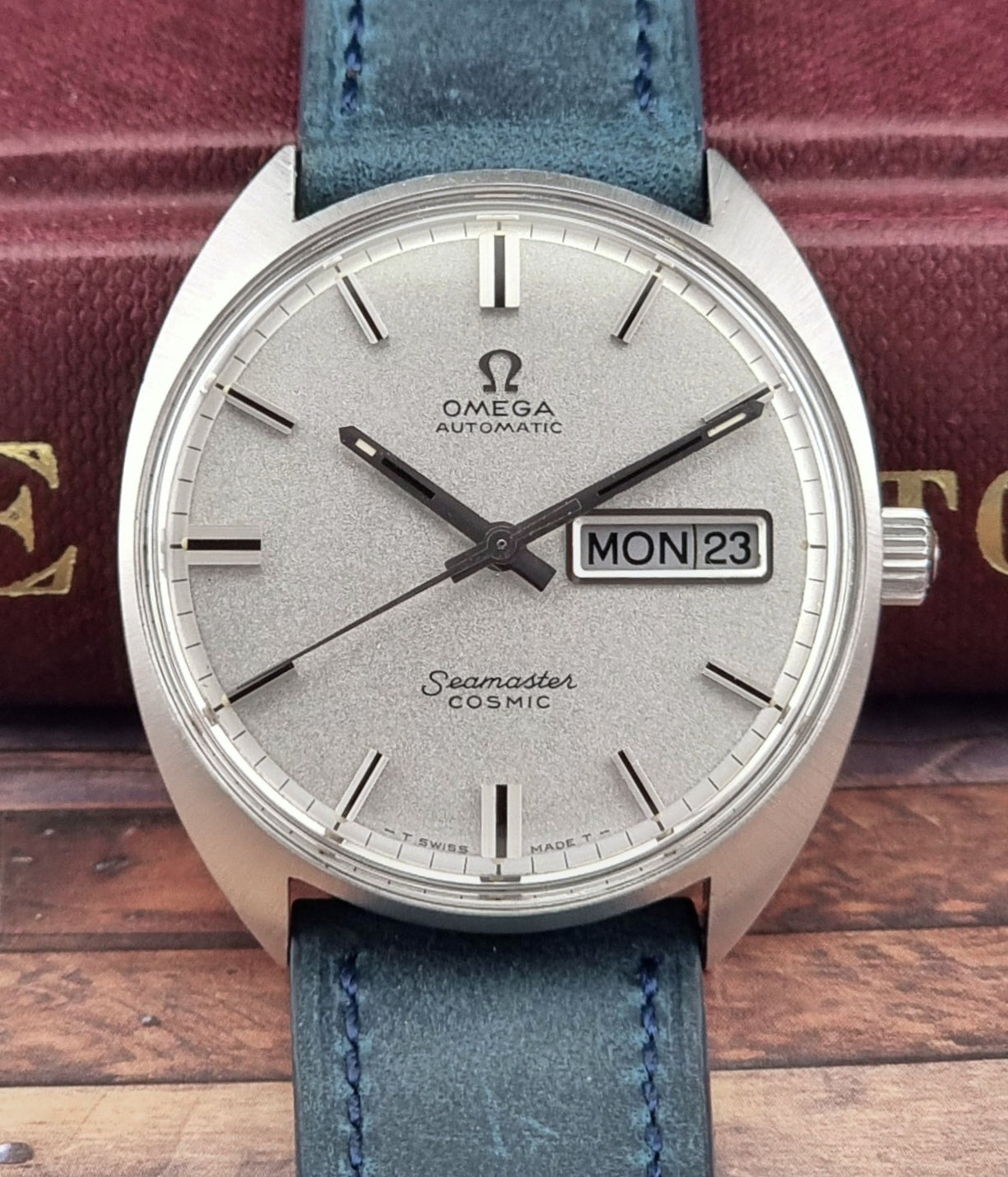 Vintage Omega Seamaster Cosmic watch with blue strap on a wooden surface