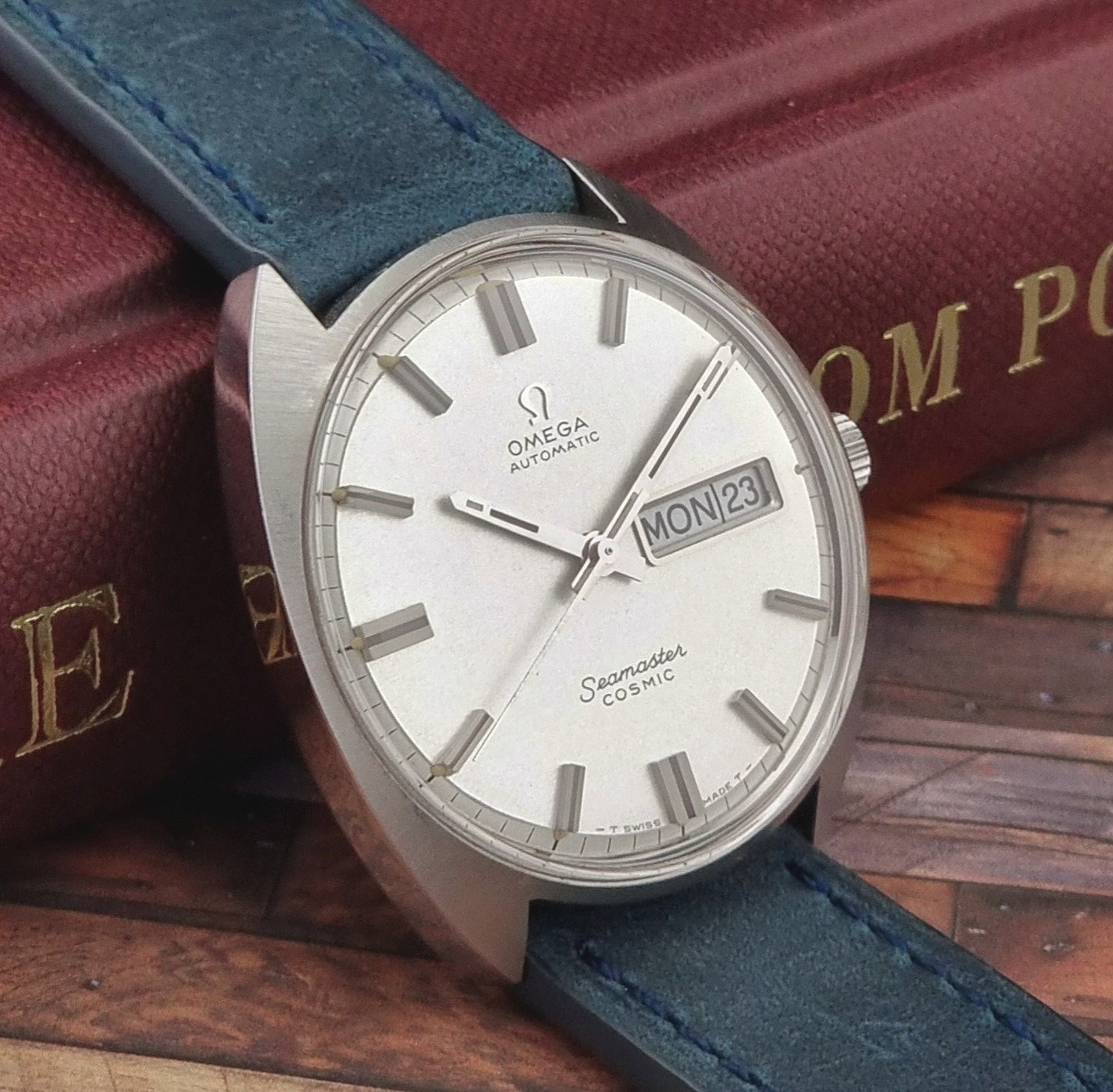 Vintage Omega Seamaster Cosmic watch with blue strap on a wooden surface