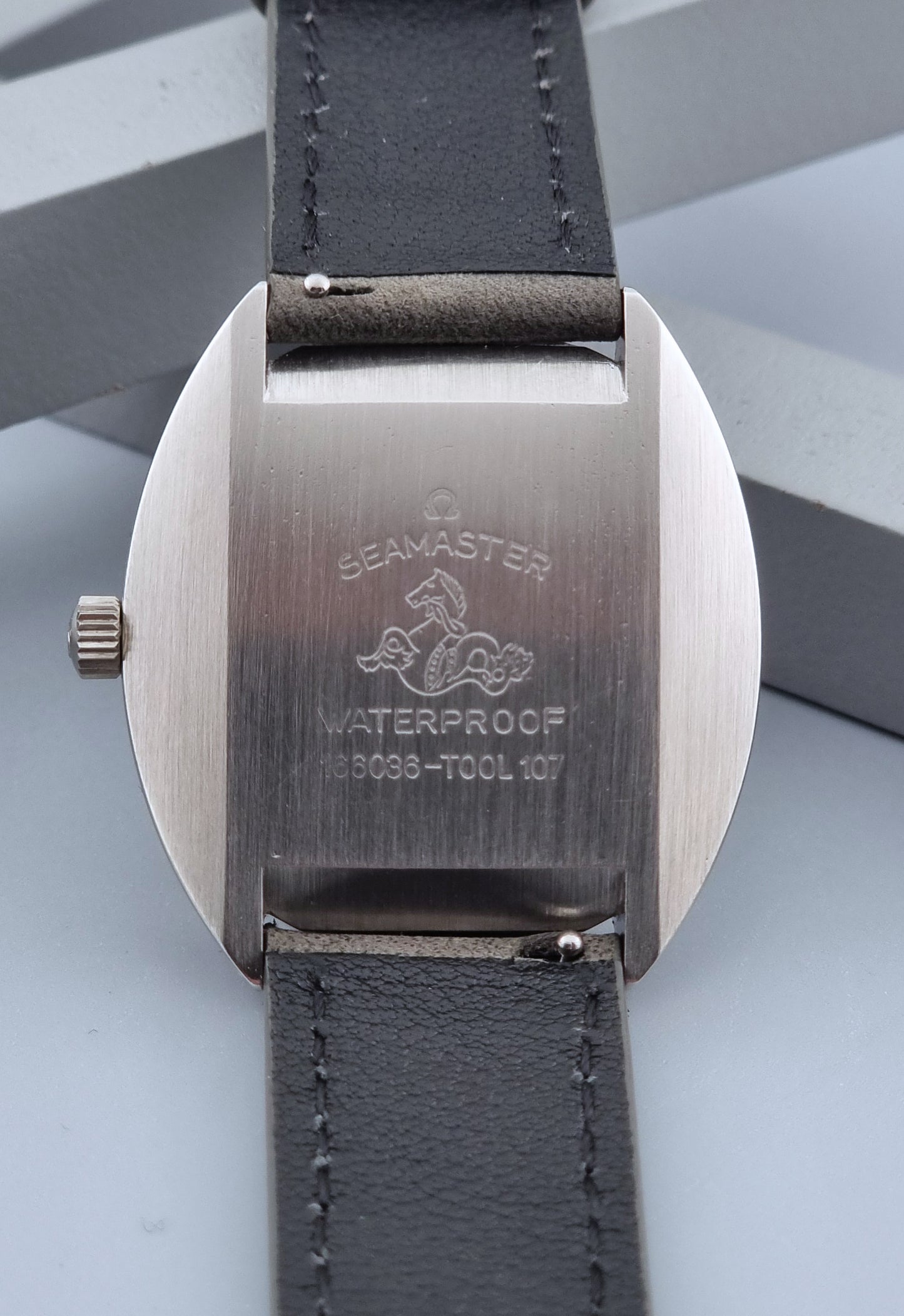 Vintage Omega Wristwatch Seamaster Cosmic 166.036 with a grey leather strap on a gray background case back